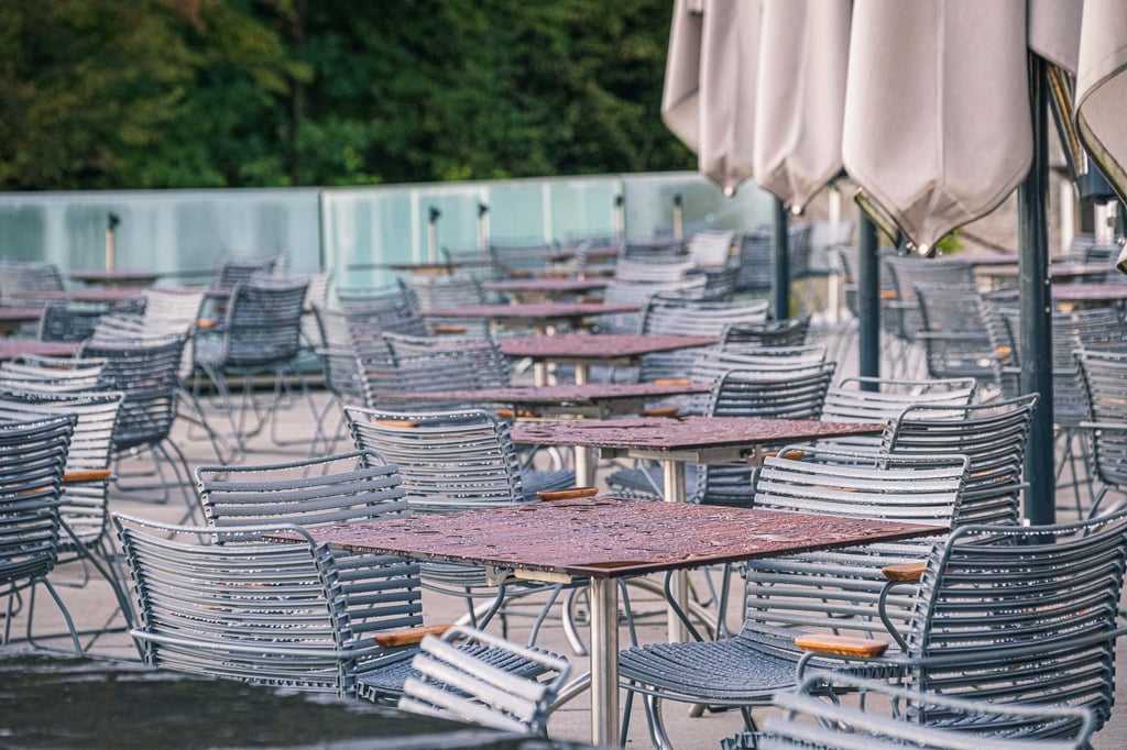 Empty tables and chairs on the terrace of Restaurant m32 with folded umbrellas on the Monchsberg in Salzburg