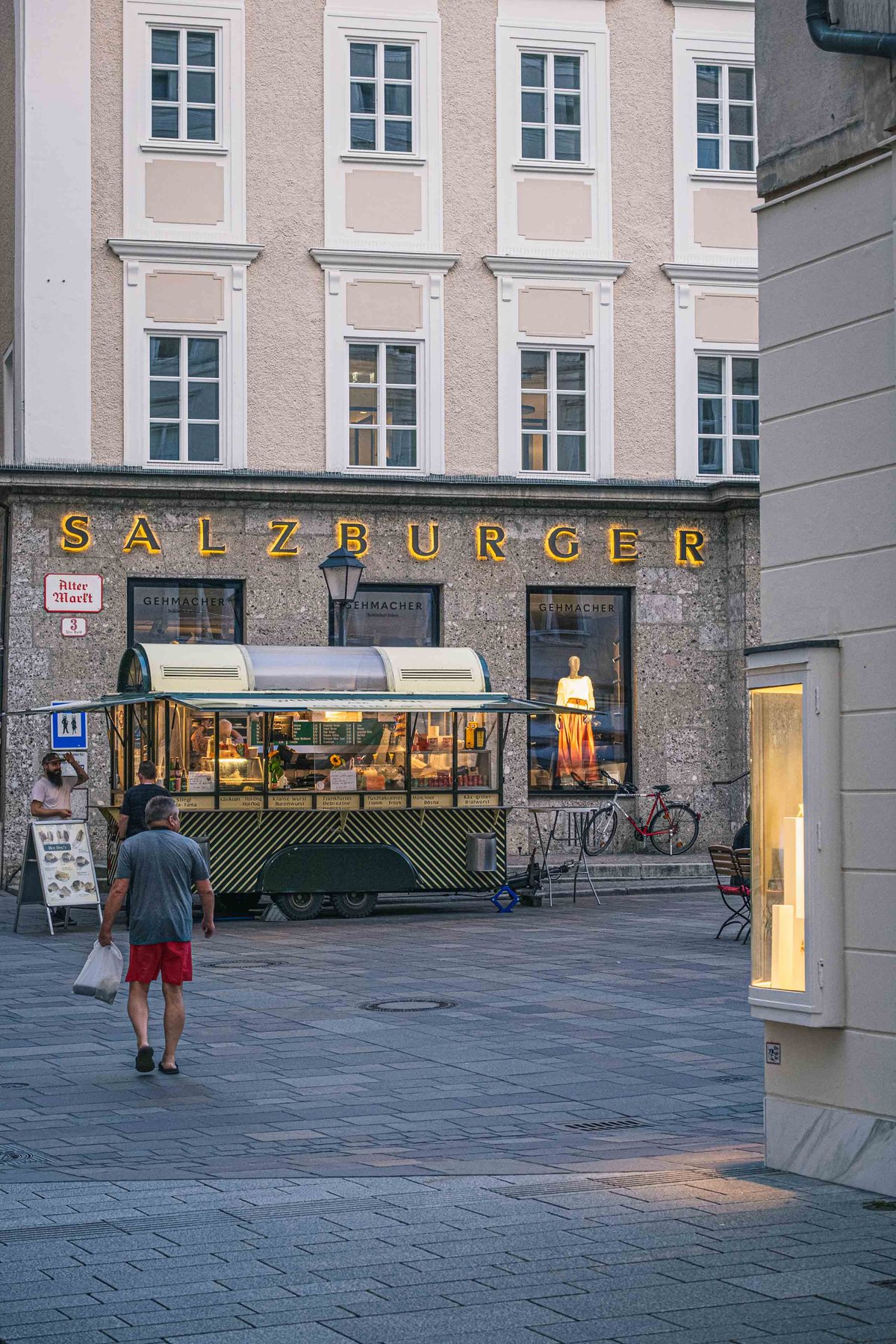 Customer walking past a building on Alter Markt in the Salzburg Altstadt at dusk
