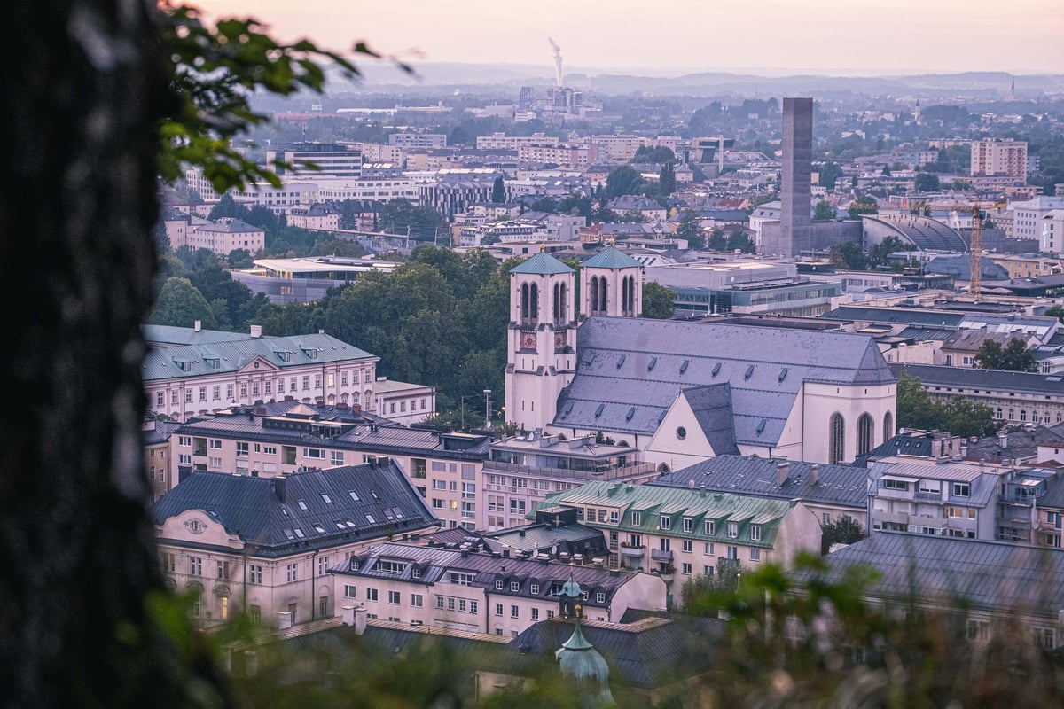 Andraekirche dome and basilica roof rising above Neustadt rooftops at dusk in Salzburg