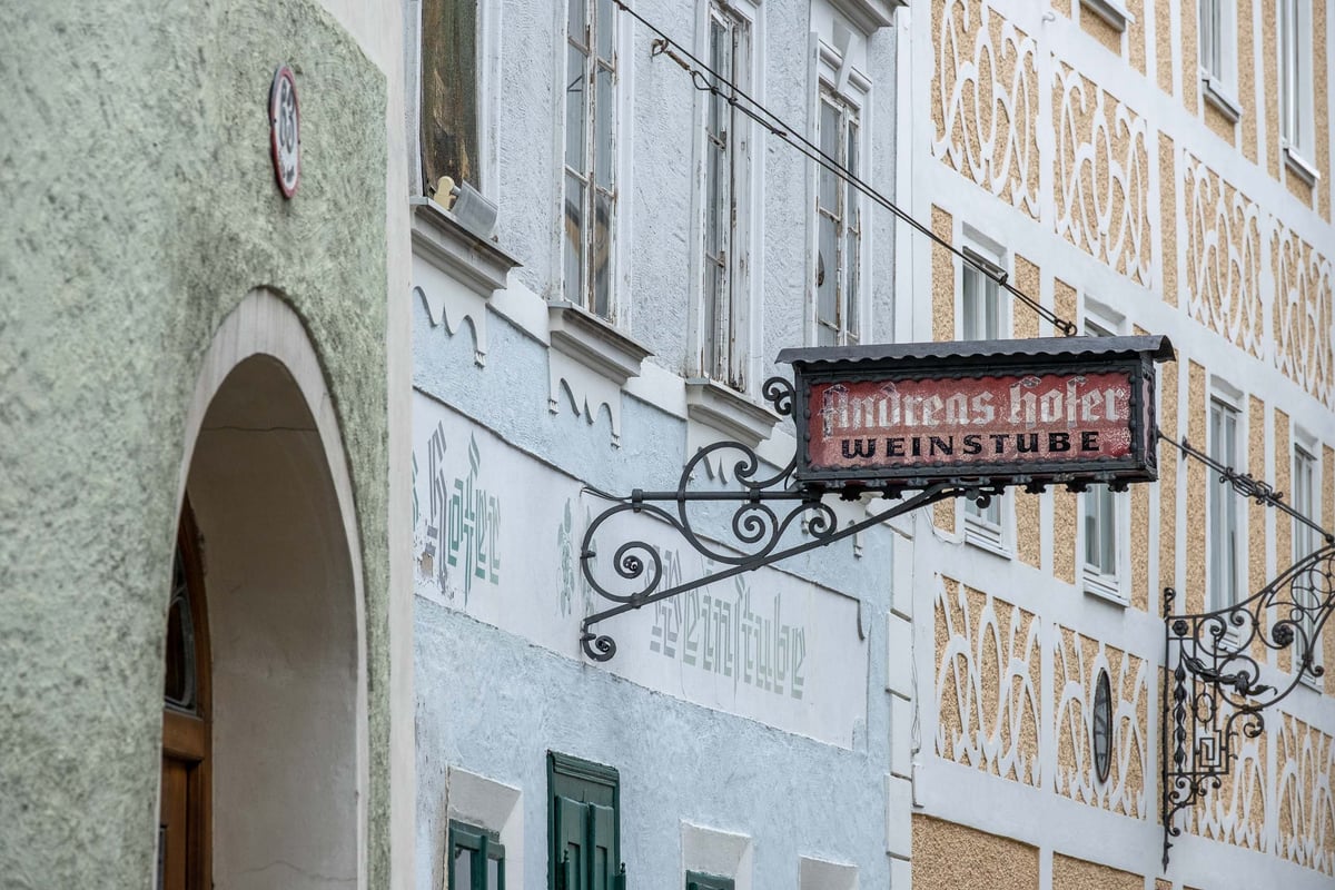 Painted Andreas Hofer Weinstube sign hangs on a sgraffito facade in Steingasse in Salzburg old town.