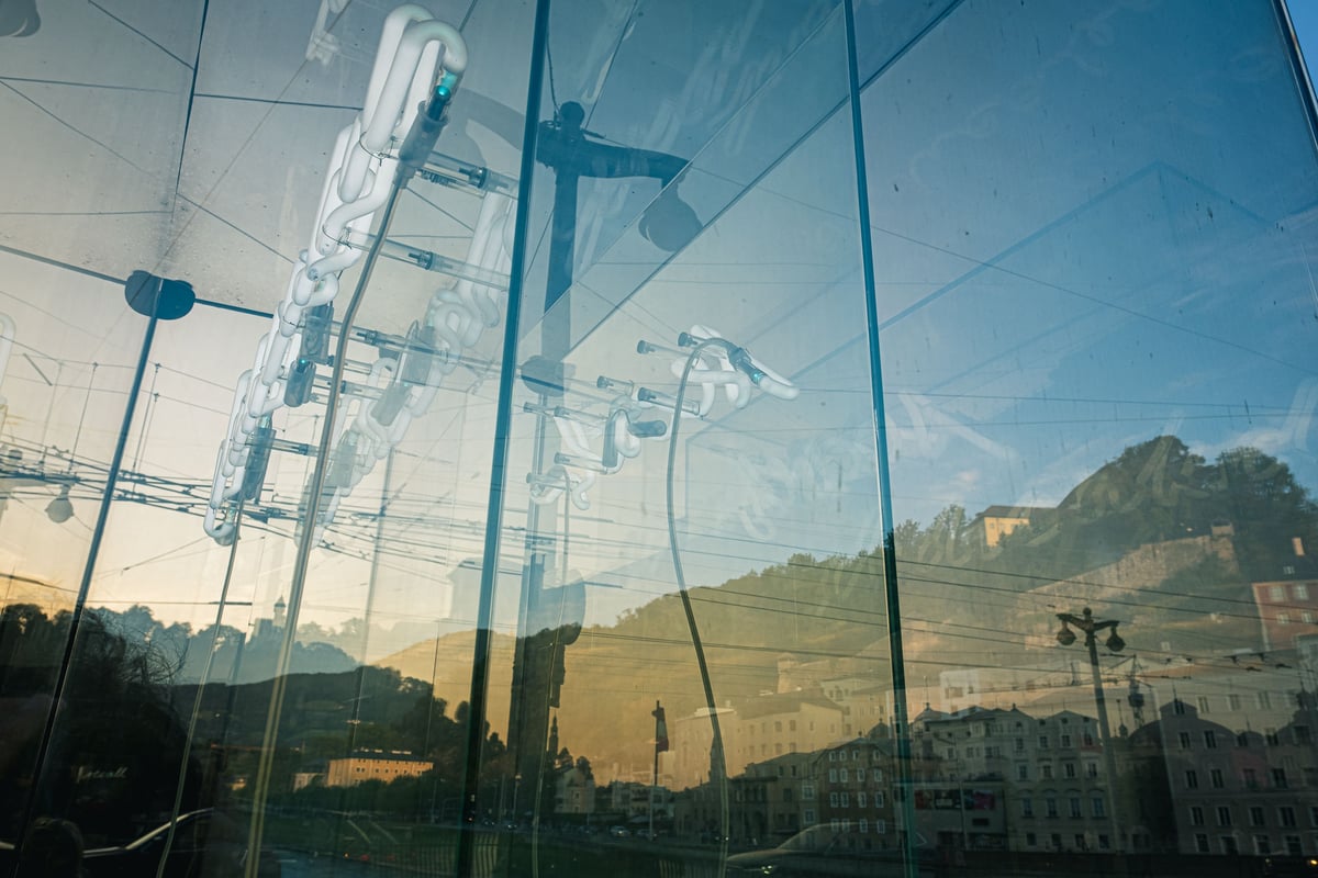 Hohensalzburg Fortress silhouette reflects through the Beyond Recall glass cube art on the Staatsbrücke in Salzburg