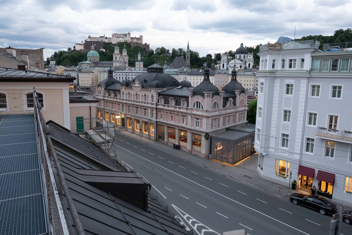 The salmon-pink Cafe Bazar building with its row of small onion-dome cupolas on Schwarzstrasse with the Salzburg fortress and old town silhouette behind