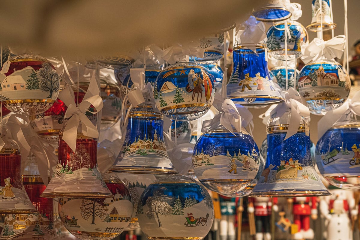 Blue and white hand-painted glass Christmas baubles with winter scenes and ribbons at a Christkindlmarkt Salzburg stall