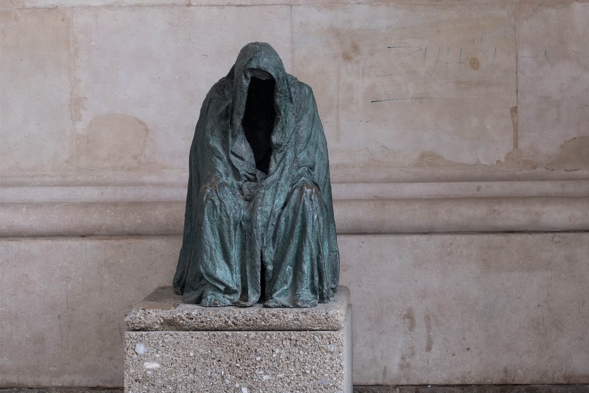 Hooded faceless bronze sculpture (Anna Chromy Cloak of Conscience or related vanitas piece) on a stone plinth in Salzburg
