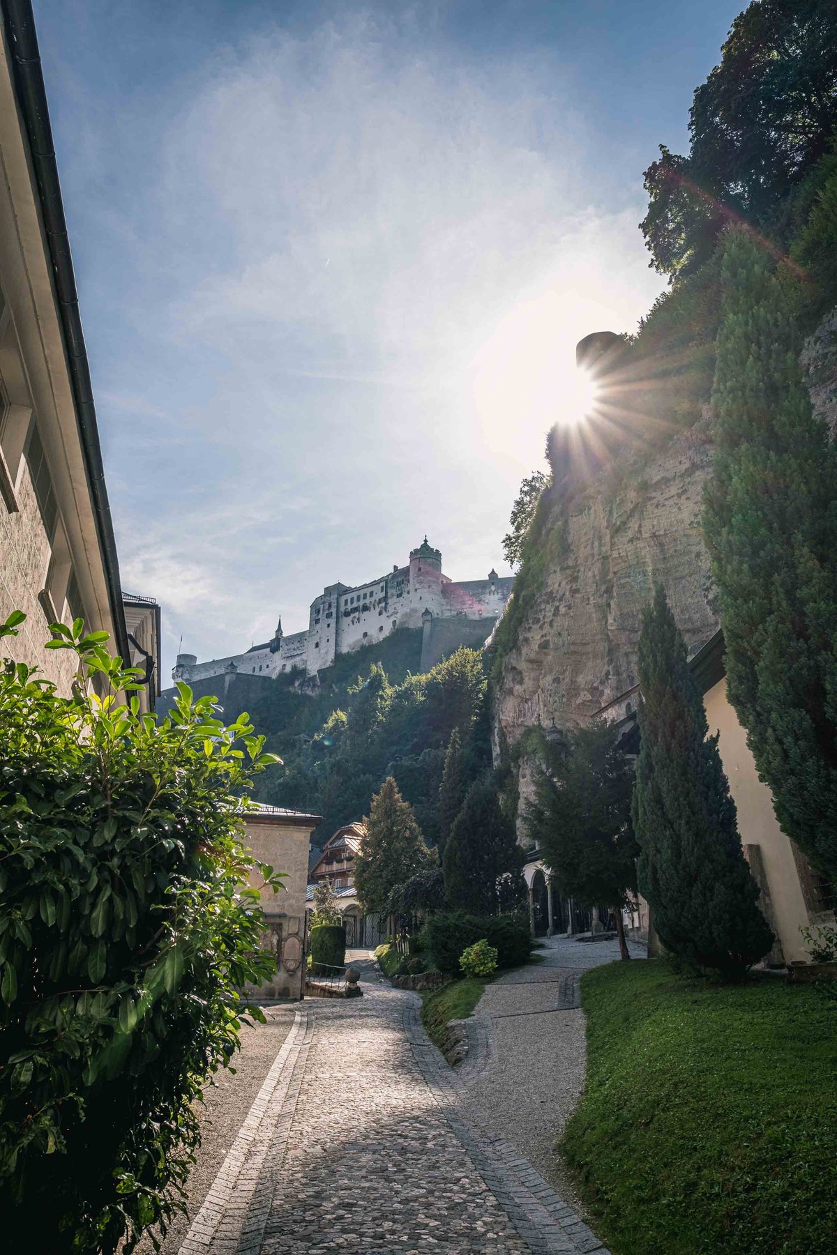 Cobbled Festungsgasse path climbs under sheer Moenchsberg cliff to the fortress in Salzburg.