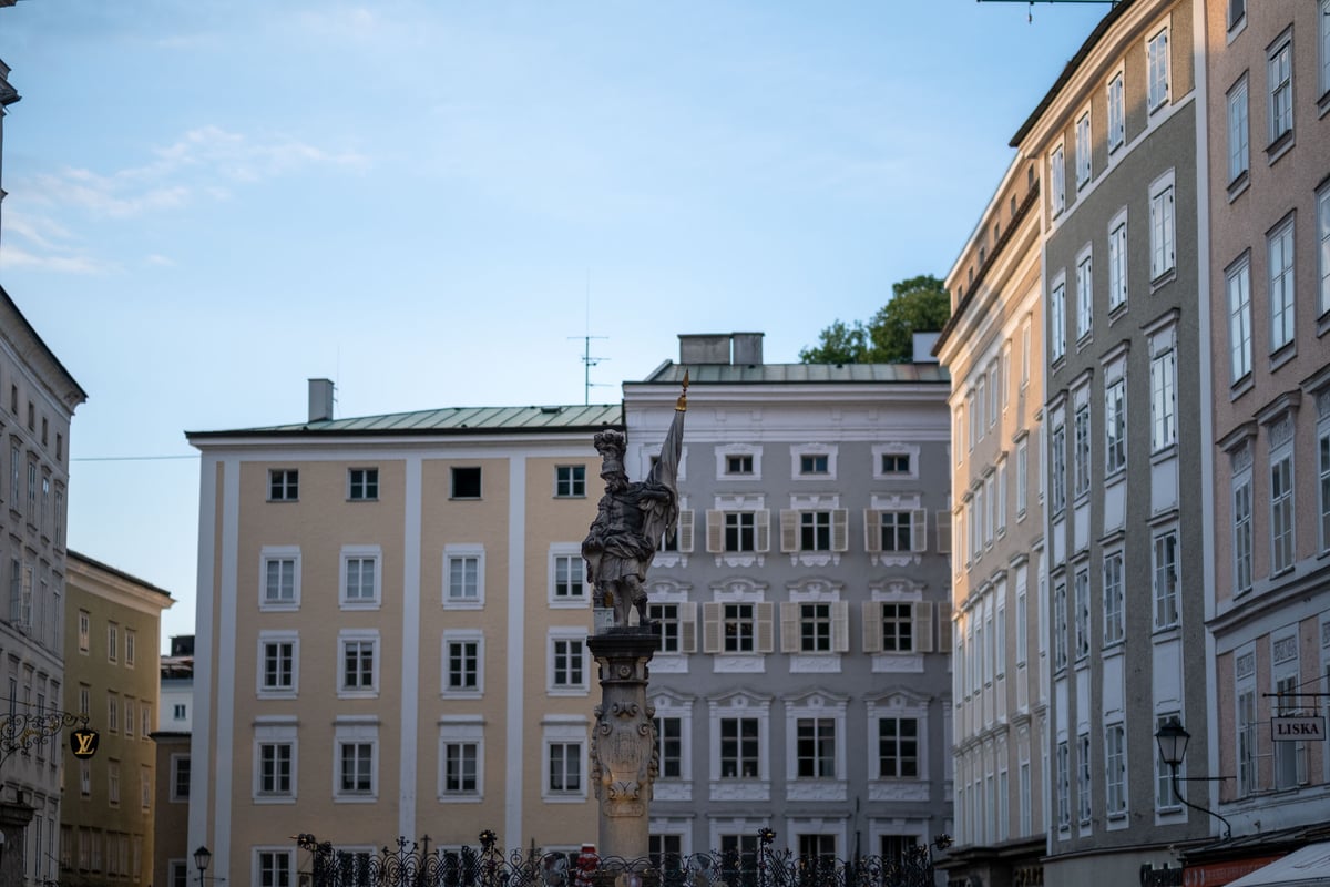 Florianibrunnen fountain statue rises above buildings on Alter Markt square in Salzburg old town.
