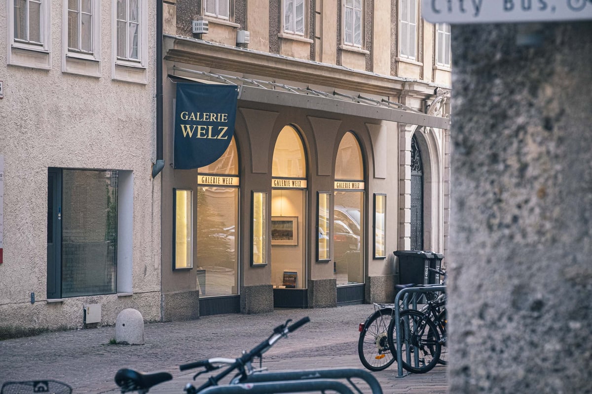 Storefront of Galerie Welz art gallery with arched windows on Sigmund Haffner Gasse in Salzburg old town.