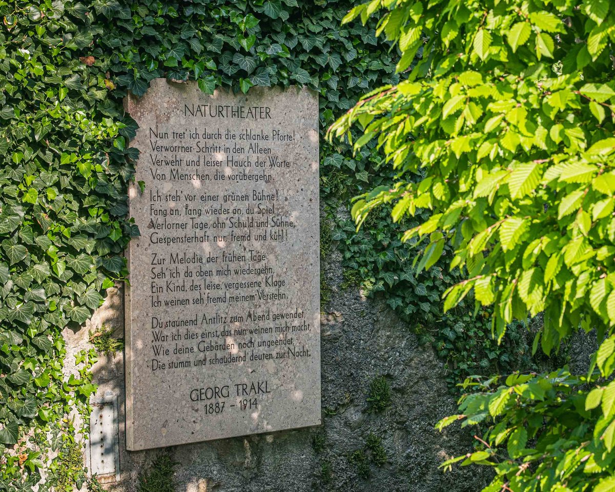 Stone plaque with the poem Naturtheater by Georg Trakl set into an ivy-covered wall in Salzburg.