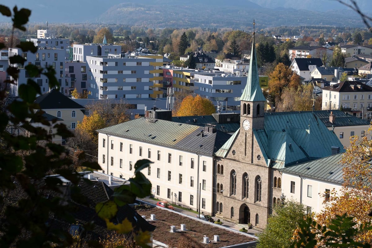 The neogothic spire of the Herz-Jesu-Asylkirche in Salzburg-Riedenburg designed by Friedrich von Schmidt and consecrated in 1878 with modern Riedenburg apartment blocks behind