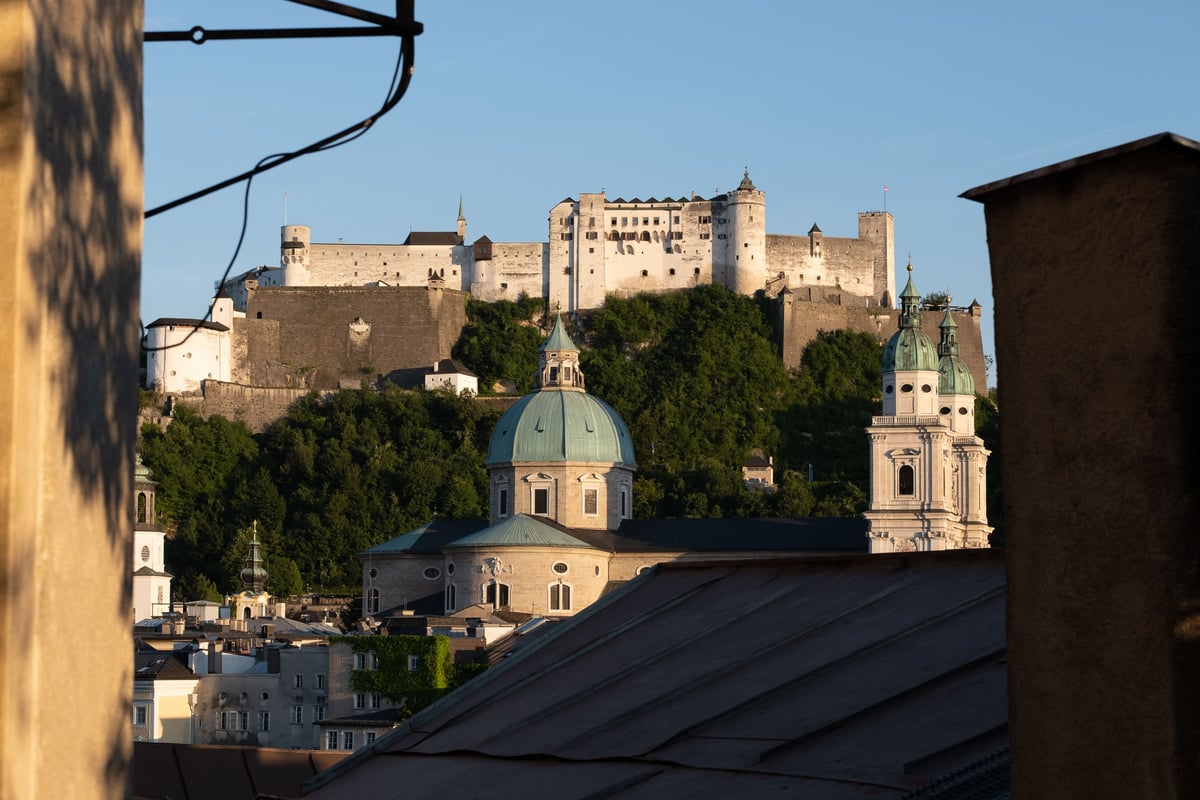 Hohensalzburg Fortress above the twin domes of Salzburg Cathedral viewed from the Neustadt in evening light