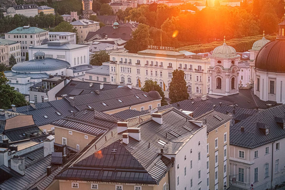 Hotel Bristol facade seen across Neustadt rooftops at sunset with Dreifaltigkeitskirche dome.