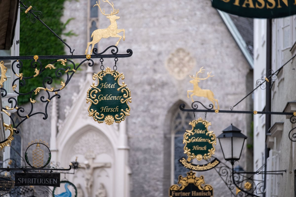Gilded wrought-iron Hotel Goldener Hirsch signs with golden stag on Getreidegasse in Salzburg