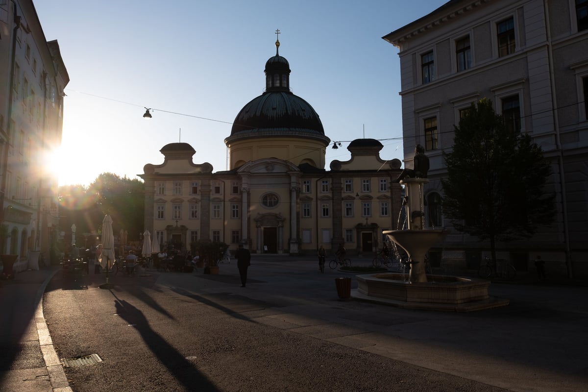 Kajetanerkirche dome and fountain on Kajetanerplatz at sunset in Salzburg old town.