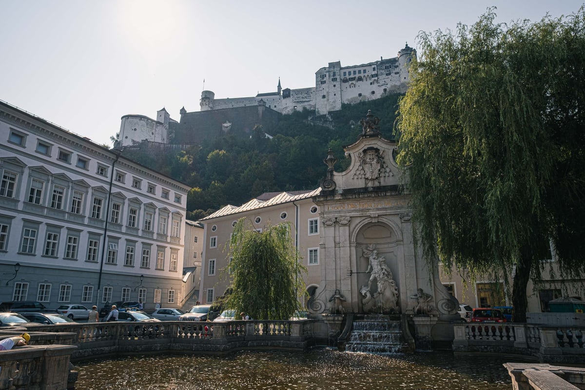 Kapitelschwemme horse pond with Hohensalzburg Fortress rising above weeping willow in Salzburg