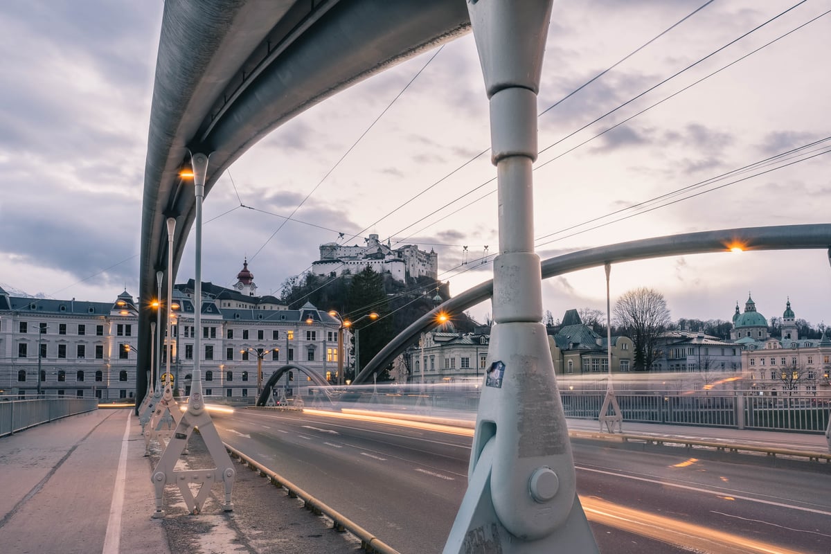View of the Hohensalzburg Fortress at dusk through the metal-arch structure of the Karolinenbruecke