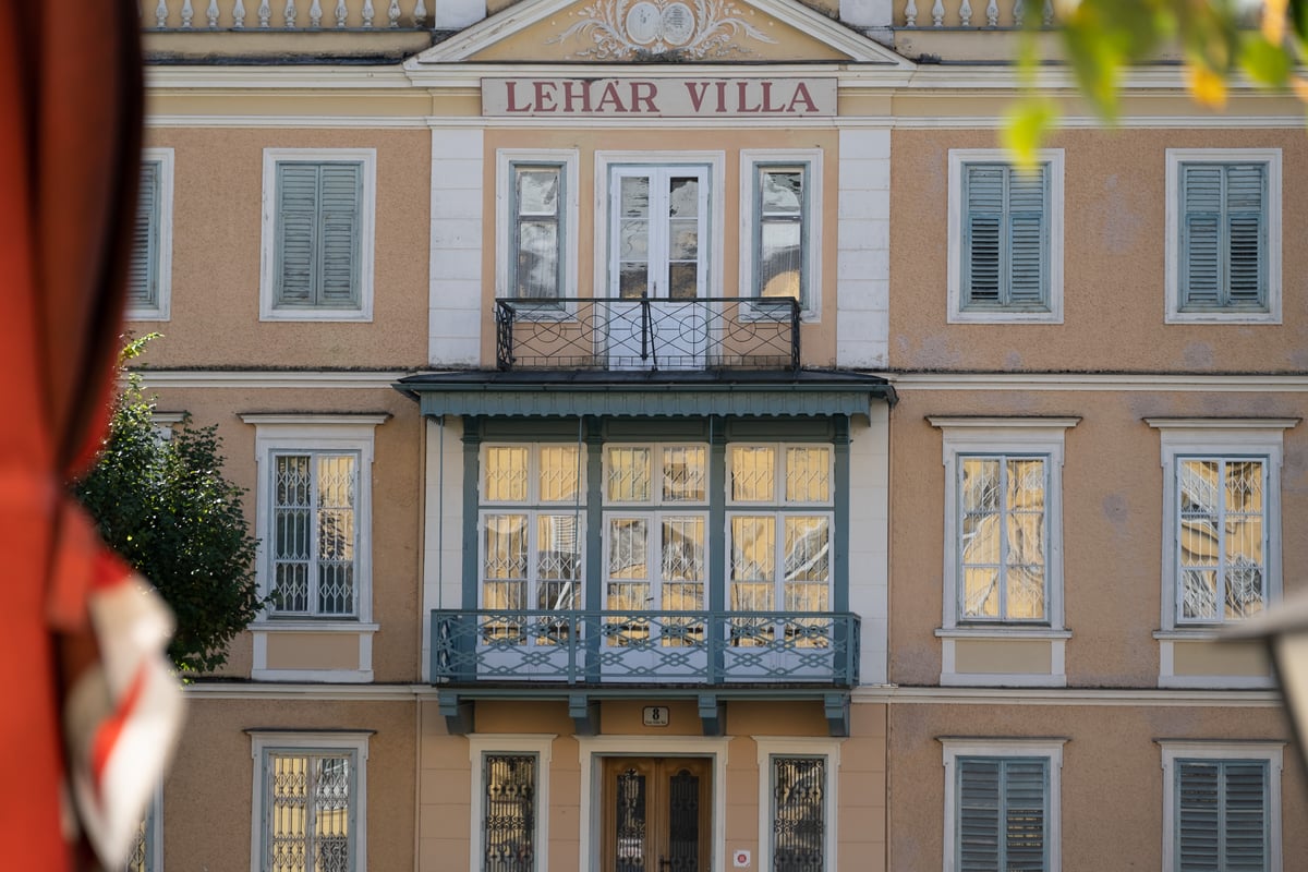 The centre of the Lehar Villa in Bad Ischl in close view, with its glazed green veranda, iron and timber balconies and the red painted LEHAR VILLA lettering under the gable.