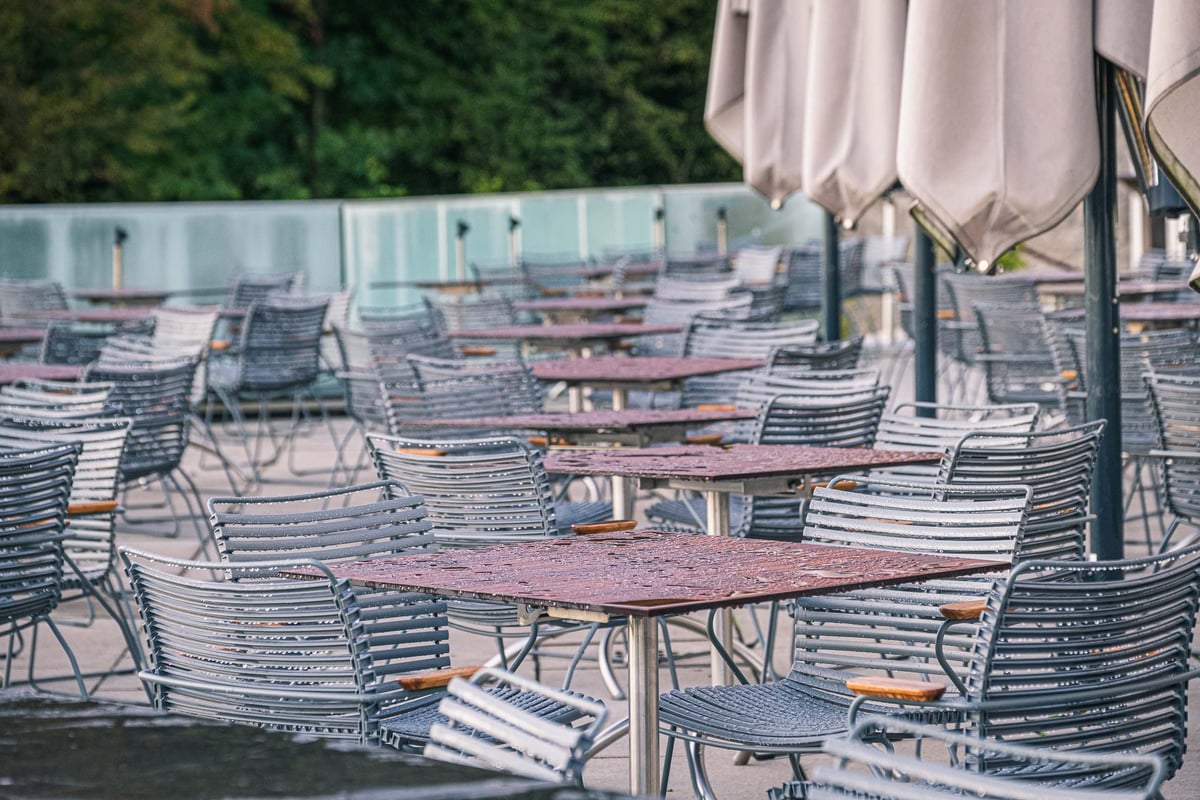 Empty tables and chairs on the terrace of Restaurant m32 with folded umbrellas on the Monchsberg in Salzburg
