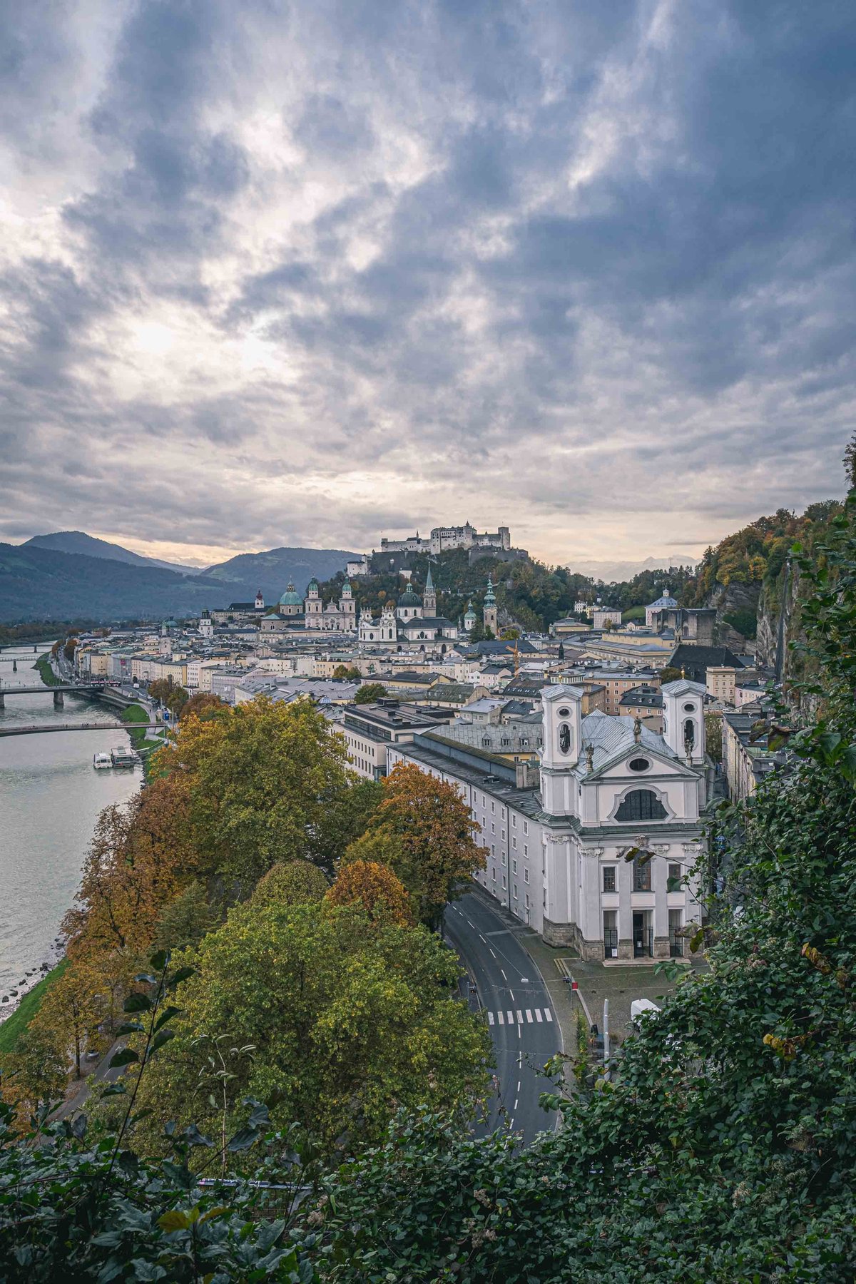 Baroque facade of Markuskirche with fortress and Salzach River in wider Salzburg old town panorama.