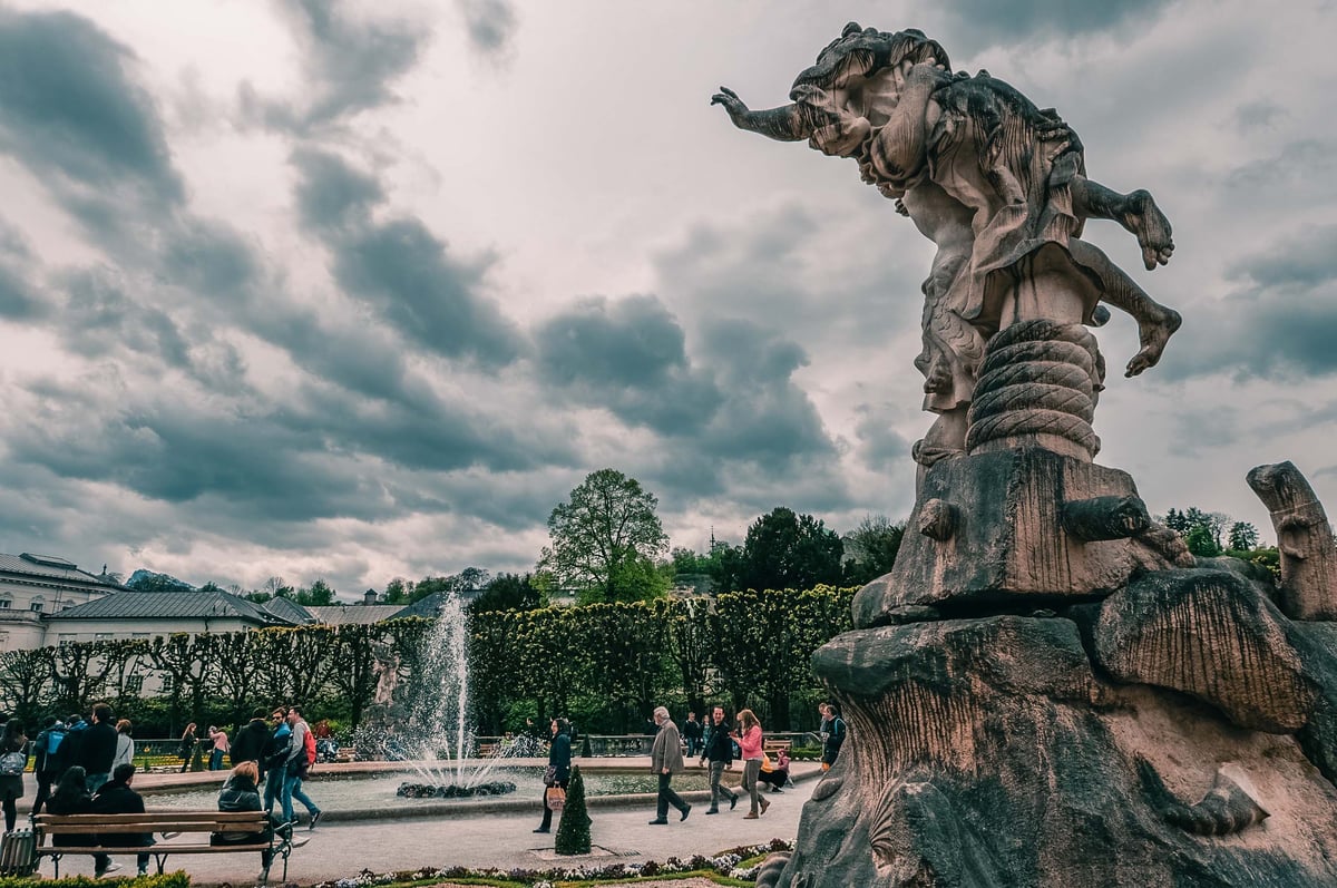 Pegasus fountain and baroque statue in Mirabell Gardens with Mirabell Palace behind in Salzburg