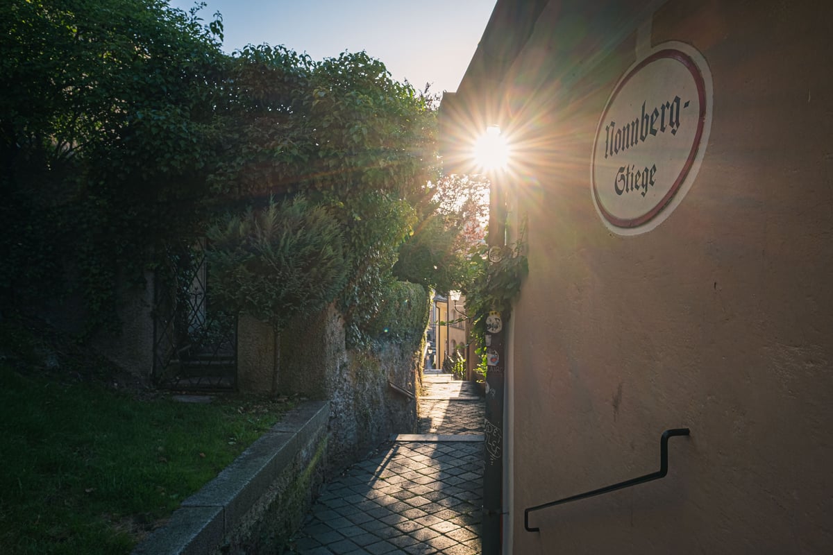 Nonnberg-Stiege street sign and narrow stepped path up toward Nonnberg Abbey at sunset in Salzburg.