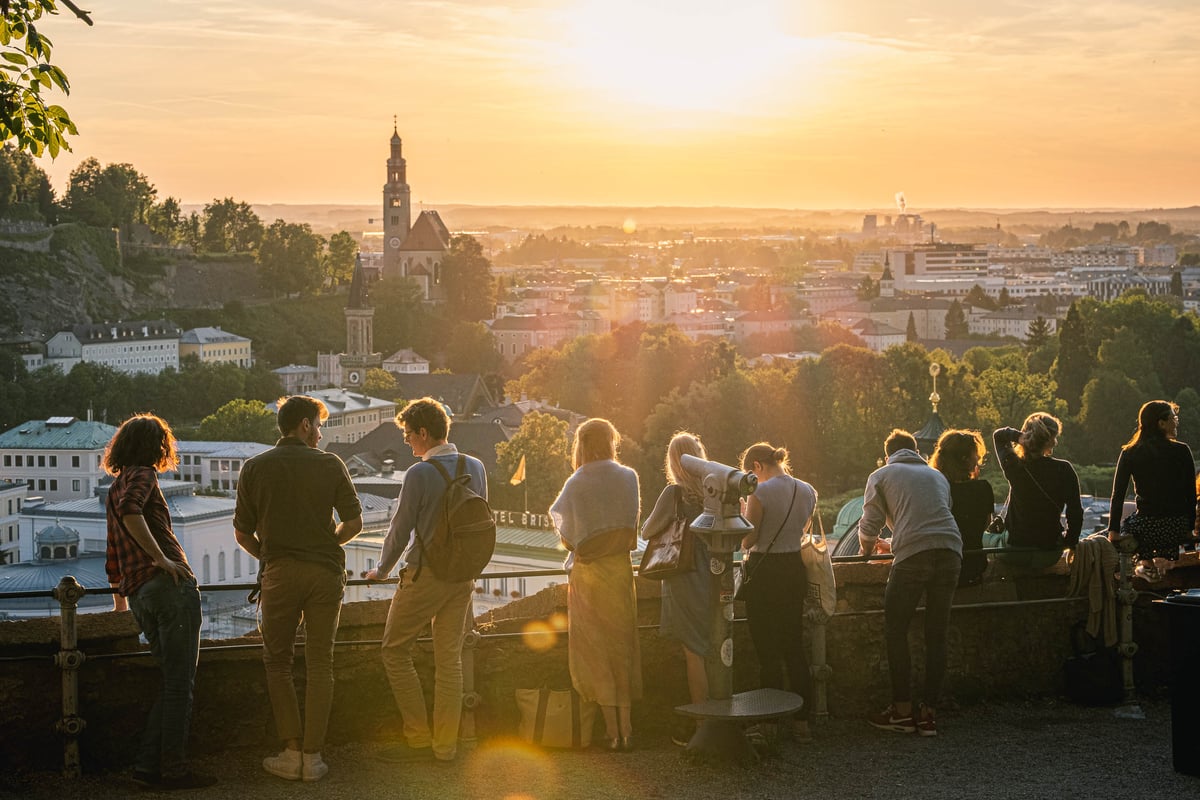 Visitors watch the sunset from a viewing terrace on Kapuzinerberg in Salzburg.