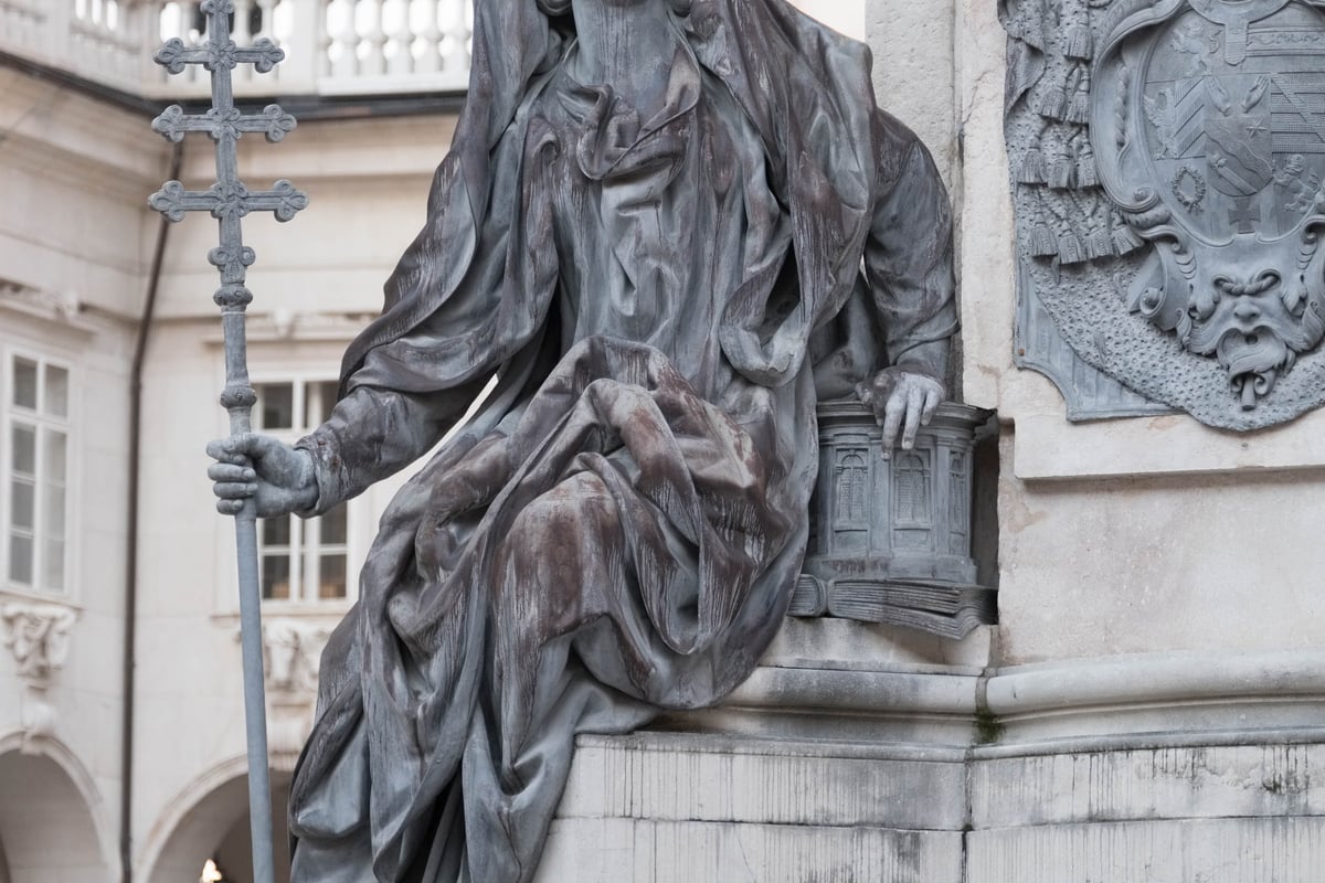 Bronze sculpture of a seated archbishop with mitre and crosier next to a coat of arms in the Residenz Salzburg