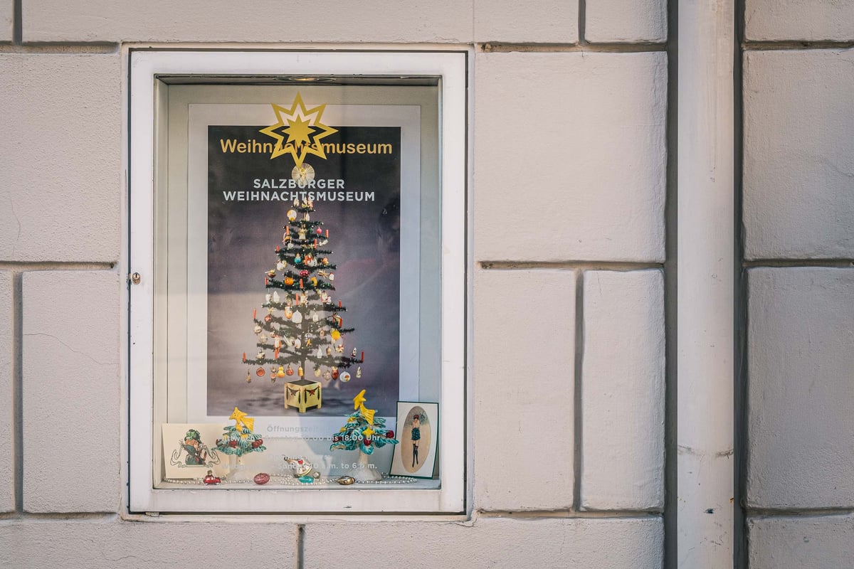 Display window with Weihnachtsmuseum poster advertising the Salzburg Christmas Museum in the old town.