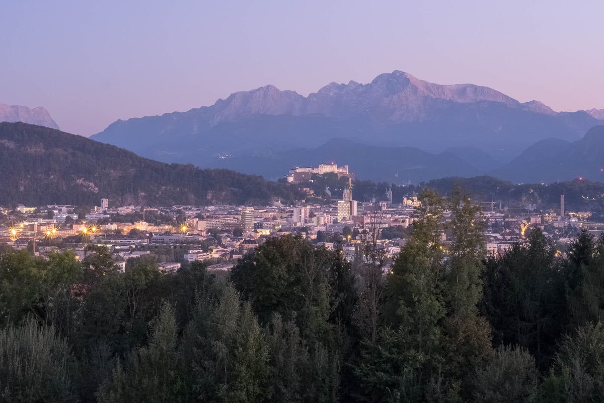 Salzburg cityscape with fortress and Untersberg mountain under pink alpenglow at dusk