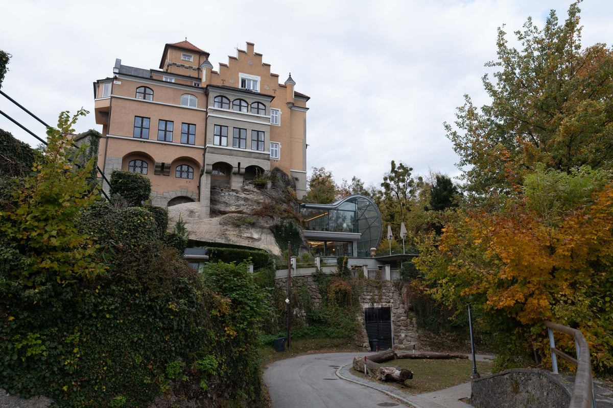 Hotel Schloss Moenchstein villa exterior on the Moenchsberg with autumn foliage and glass lift in Salzburg.
