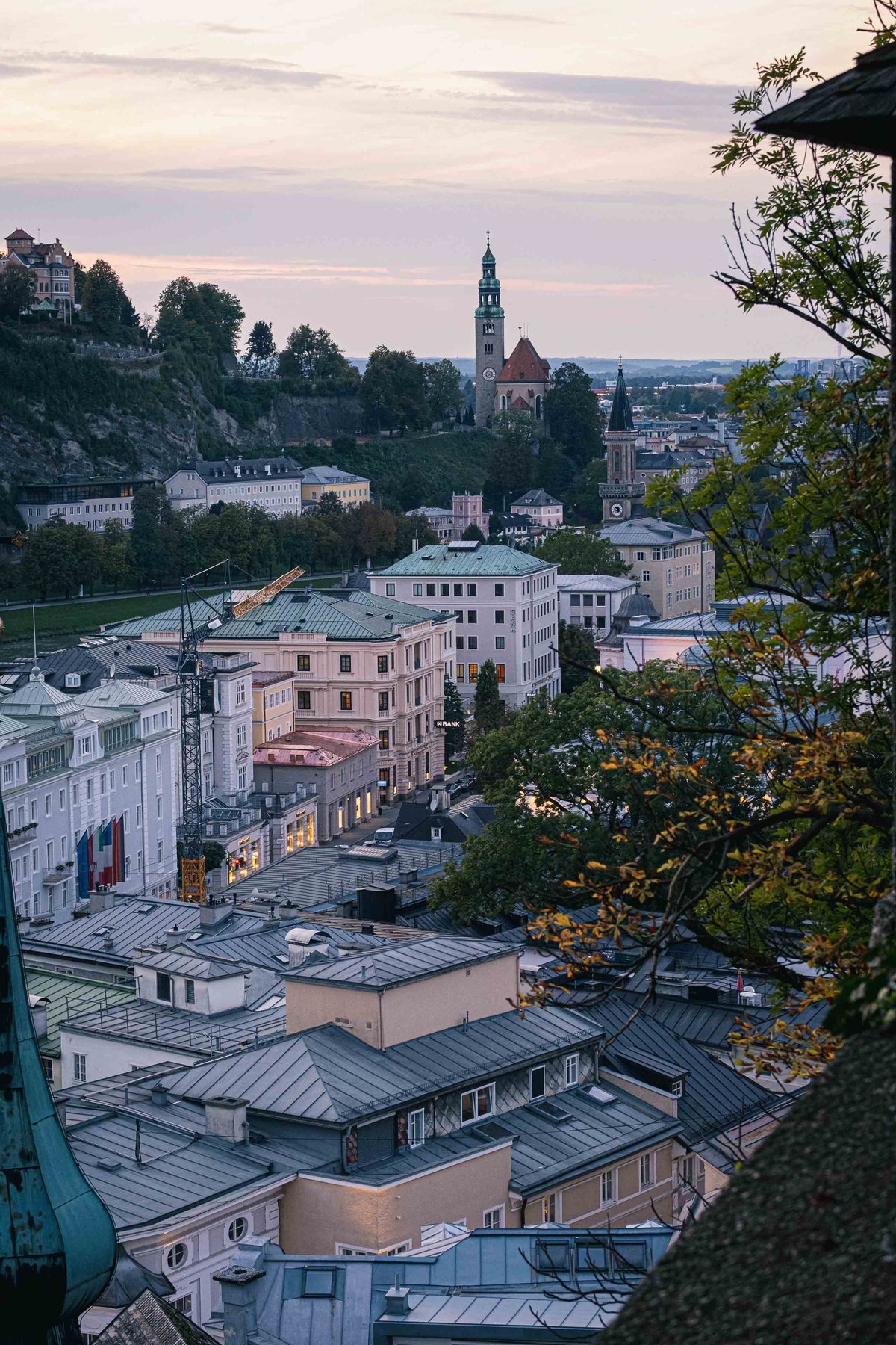 View from Kapuzinerberg over Salzburg Altstadt rooftops at dusk with the Schwarzstrasse area visible across the river