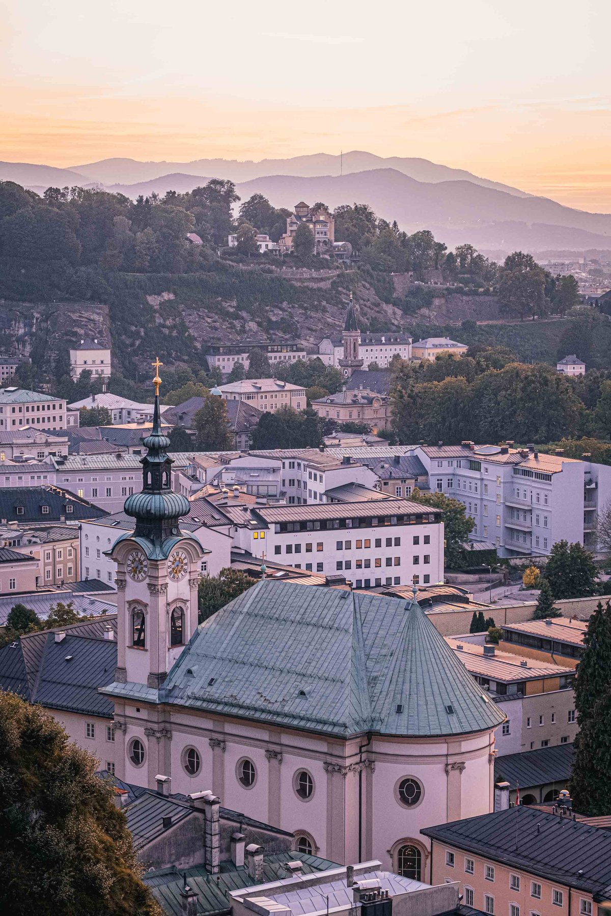 Sebastianskirche green-domed church rising above Neustadt rooftops at sunset in Salzburg