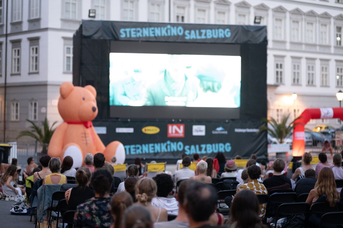 Sternenkino Salzburg open-air cinema with audience and large teddy bear in Salzburg.