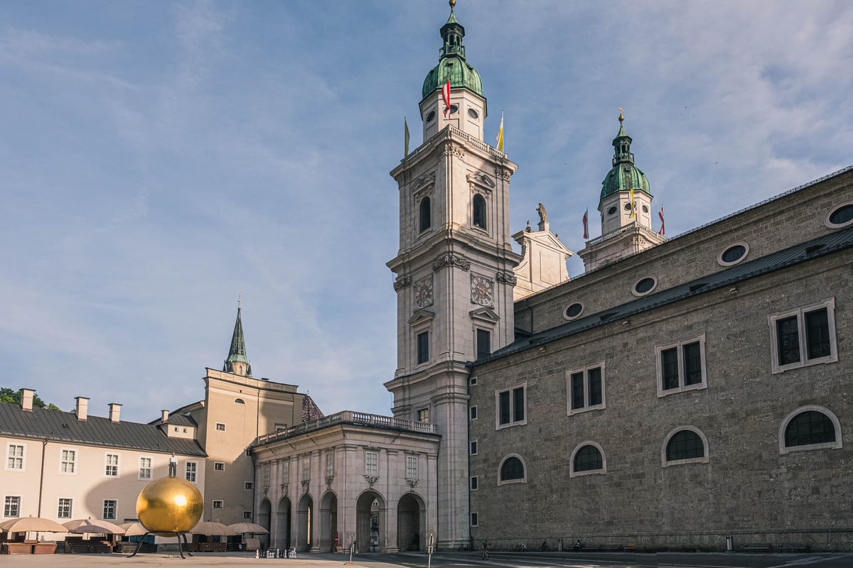 Sphaera golden ball sculpture in front of Salzburg Cathedral towers on Kapitelplatz in Salzburg
