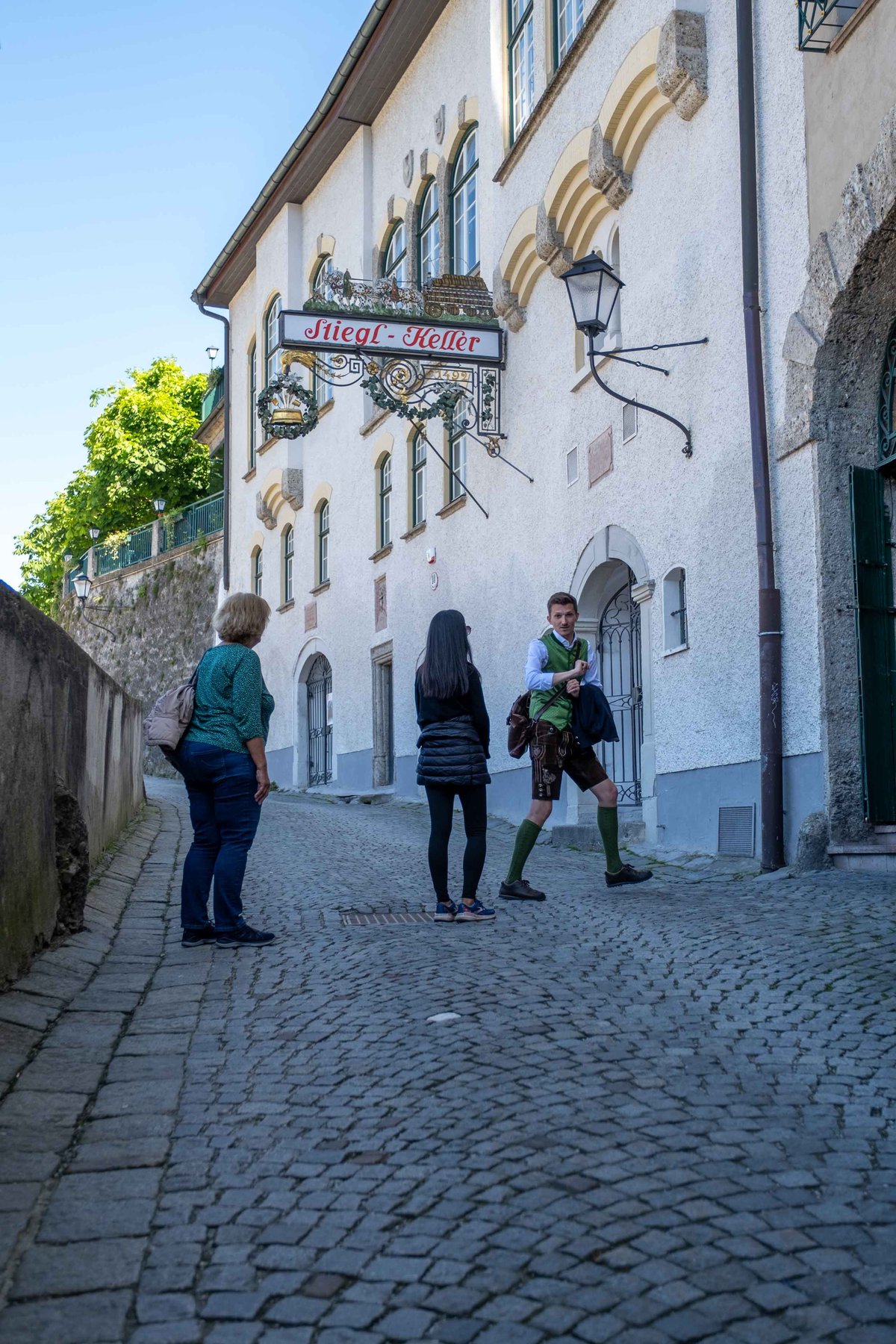 Guests in traditional dress stand on the cobbled alley outside Stieglkeller beer garden in Salzburg