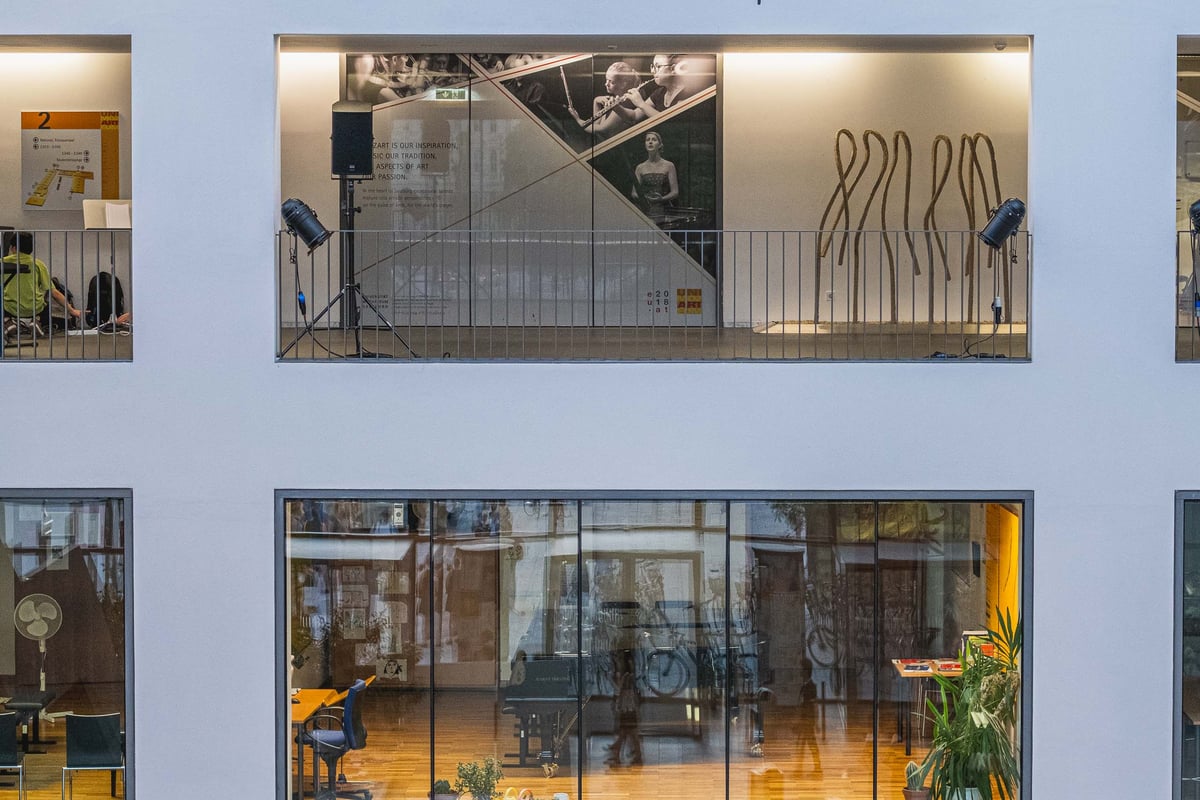 Multi-level interior of the Universitaet Mozarteum atrium with glass walls performance posters and stage lighting equipment in Salzburg