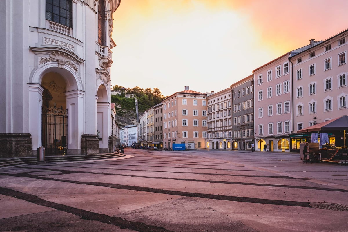 Universitatsplatz square with the curved apse of Kollegienkirche at sunset in Salzburg old town.