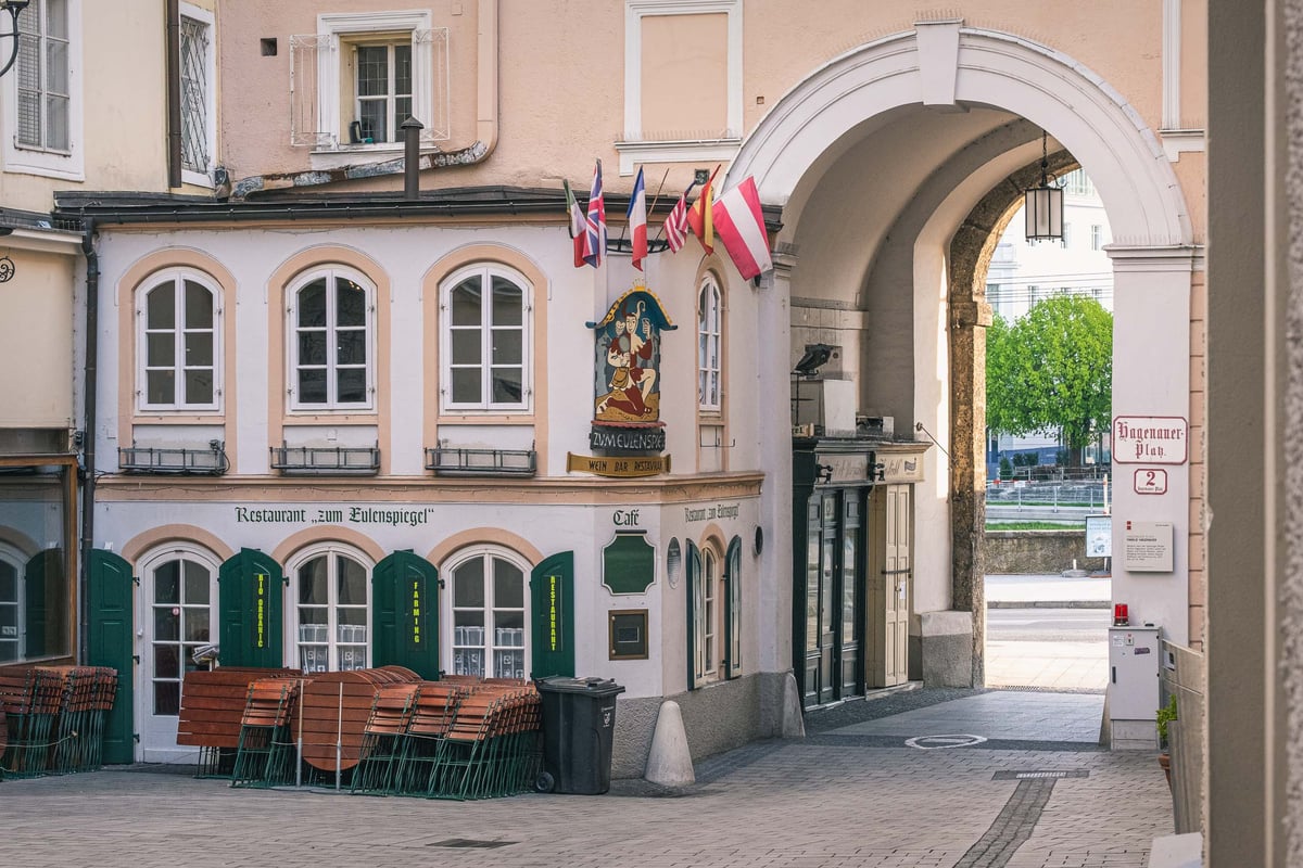Restaurant Zum Eulenspiegel with painted sign and archway at Hagenauerplatz in Salzburg old town.