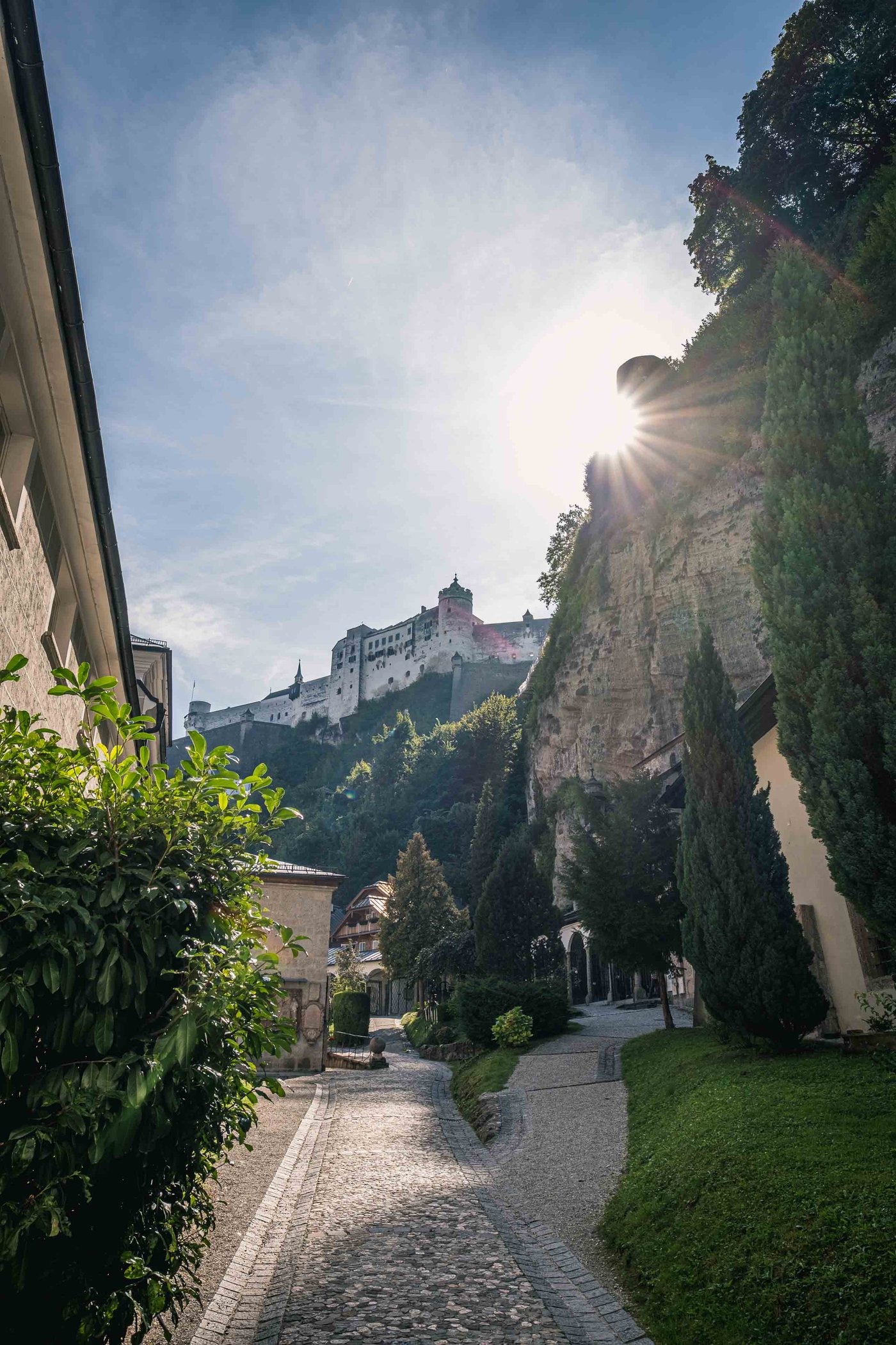 Cobbled Festungsgasse path climbs under sheer Moenchsberg cliff to the fortress in Salzburg.
