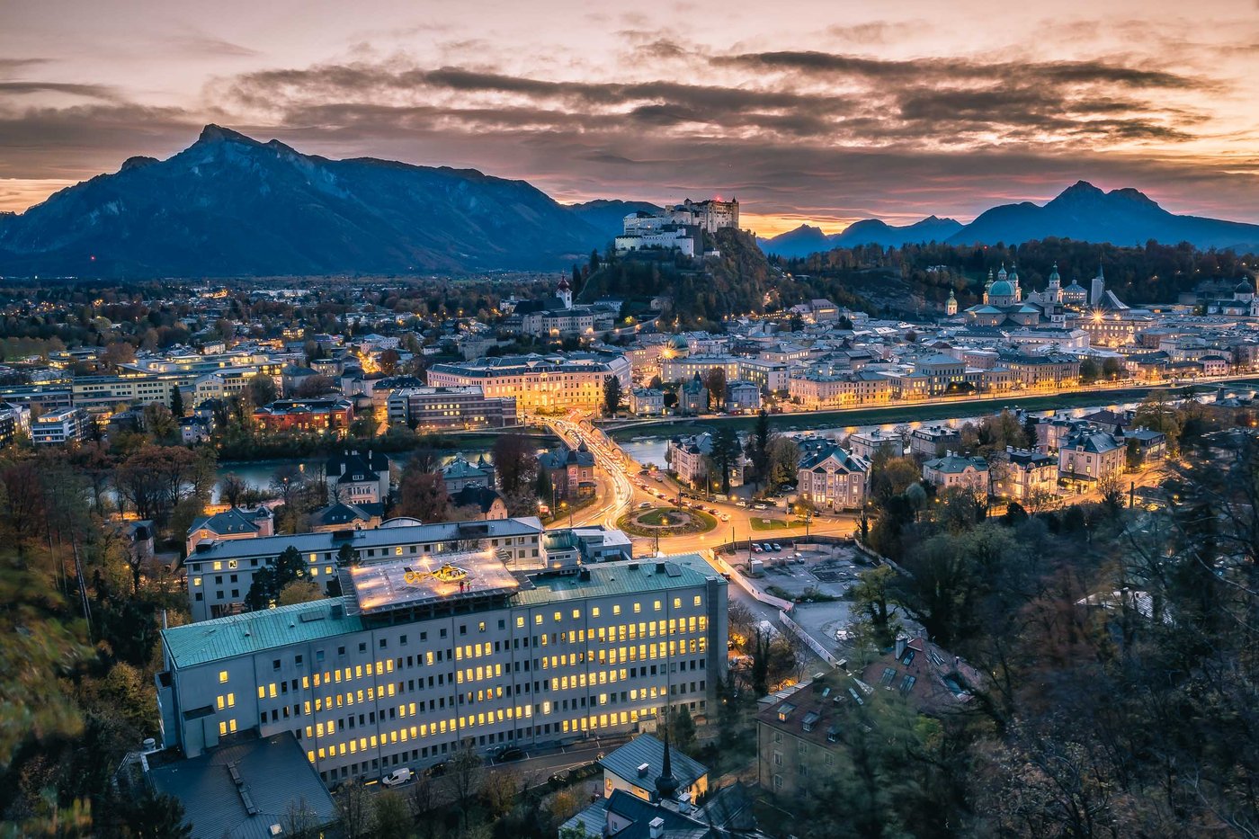 Dusk panorama from Kapuzinerberg over Altstadt rooftops and Hohensalzburg Fortress in Salzburg.