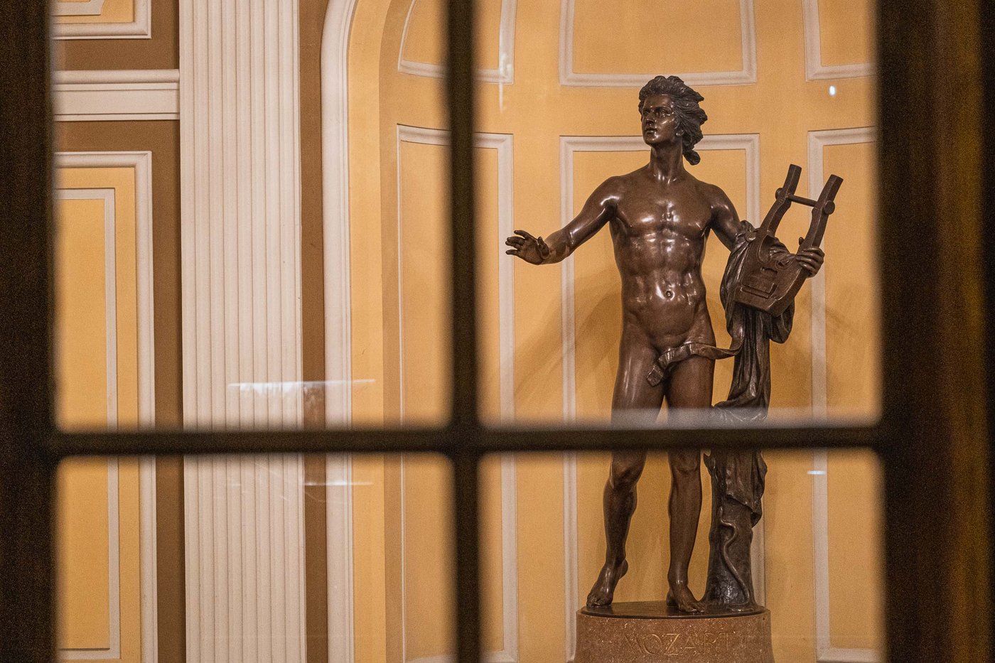 Bronze Apollo with lyre statue seen through a window at the Stiftung Mozarteum / Mozarteum Foundation building in Salzburg