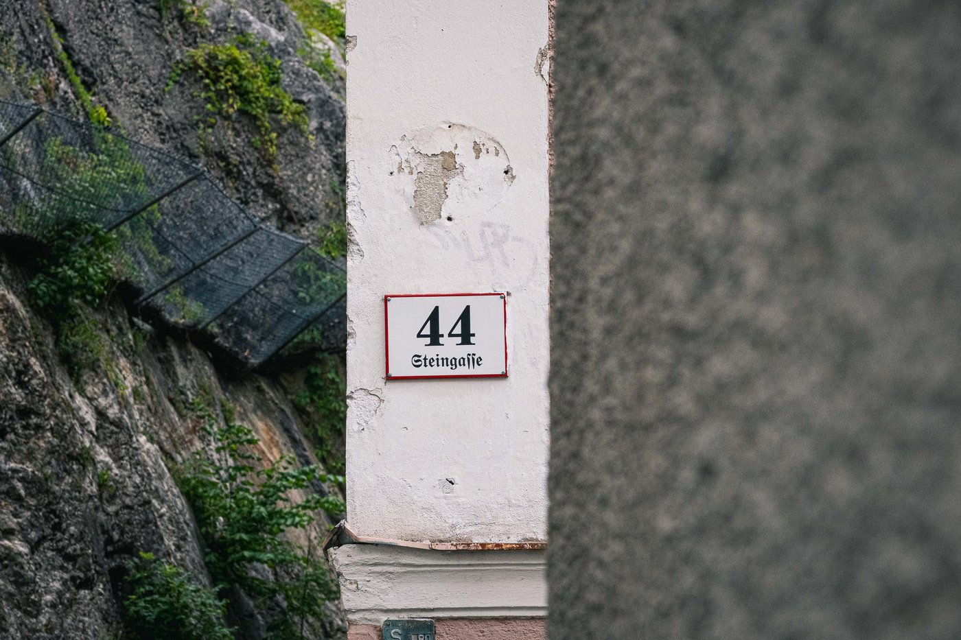 Enamel house number 44 marks a weathered facade on Steingasse in Salzburg old town.