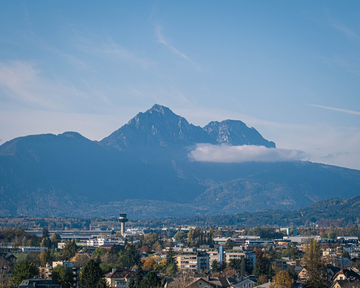 The Untersberg massif rises behind the Salzburg airport control tower on a clear autumn day.