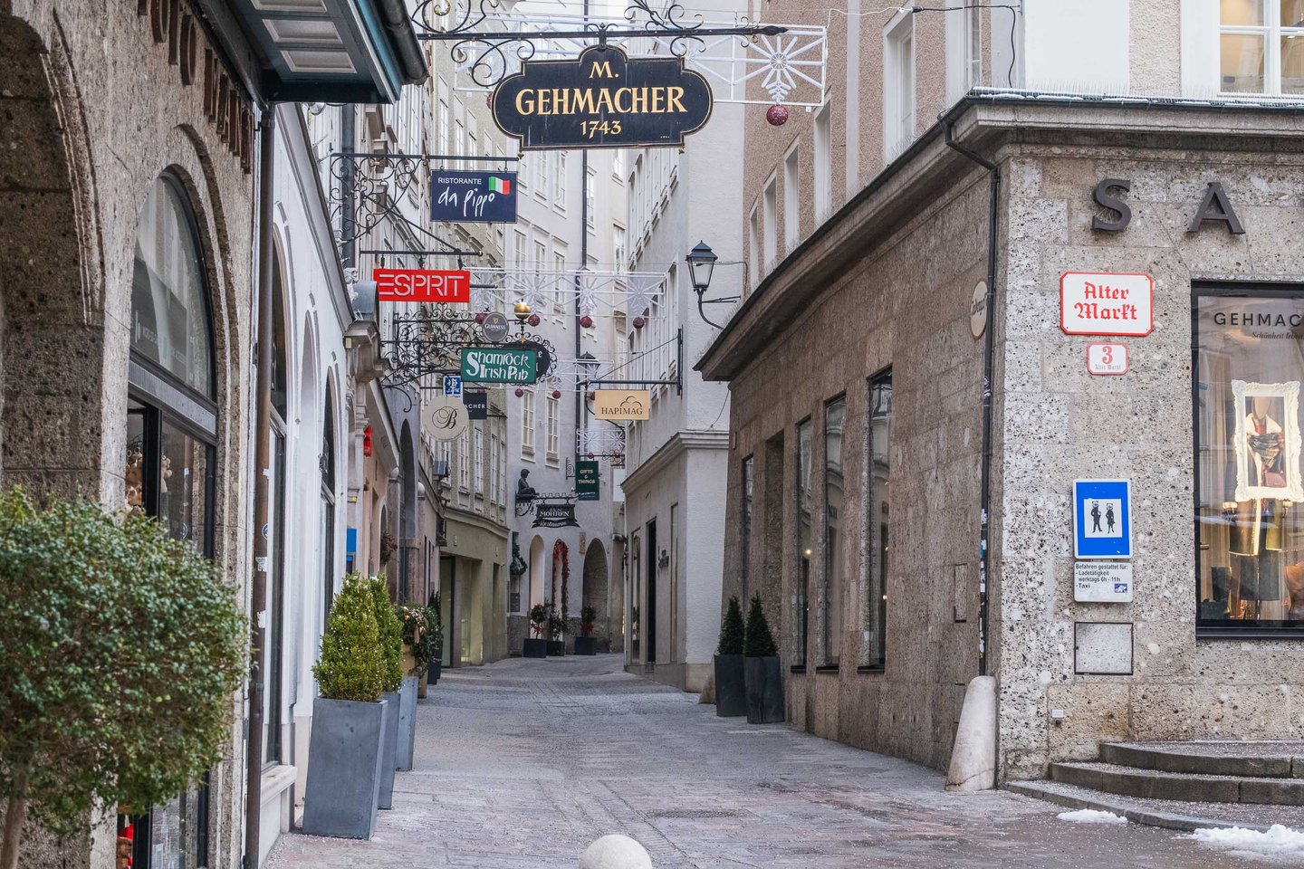 M Gehmacher 1743 ornate hanging sign and Alter Markt 3 address plaque on a narrow alley in Salzburg old town.