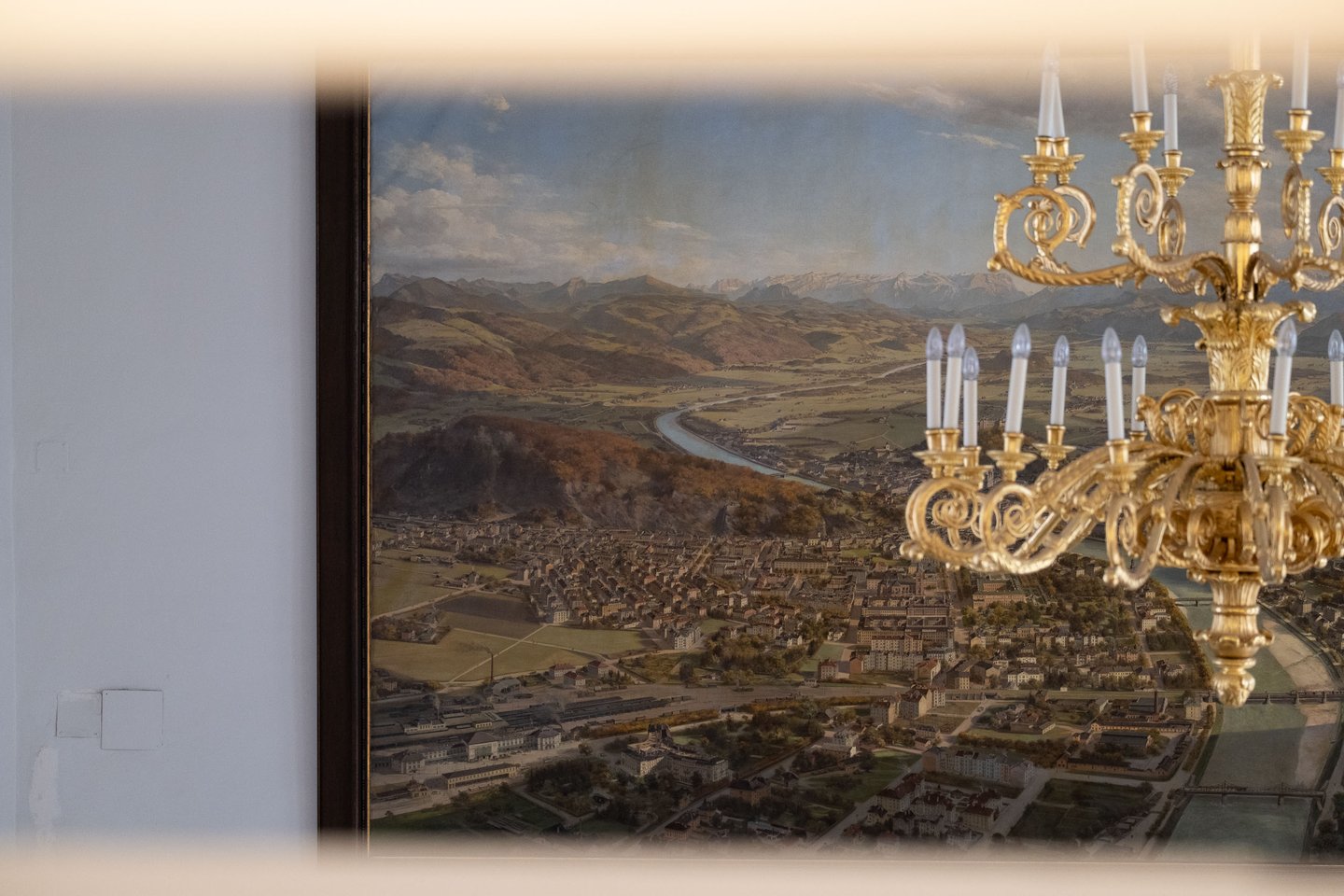 Gilded chandelier partly obscuring the Kulstrunk panorama painting at the Altes Rathaus Salzburg