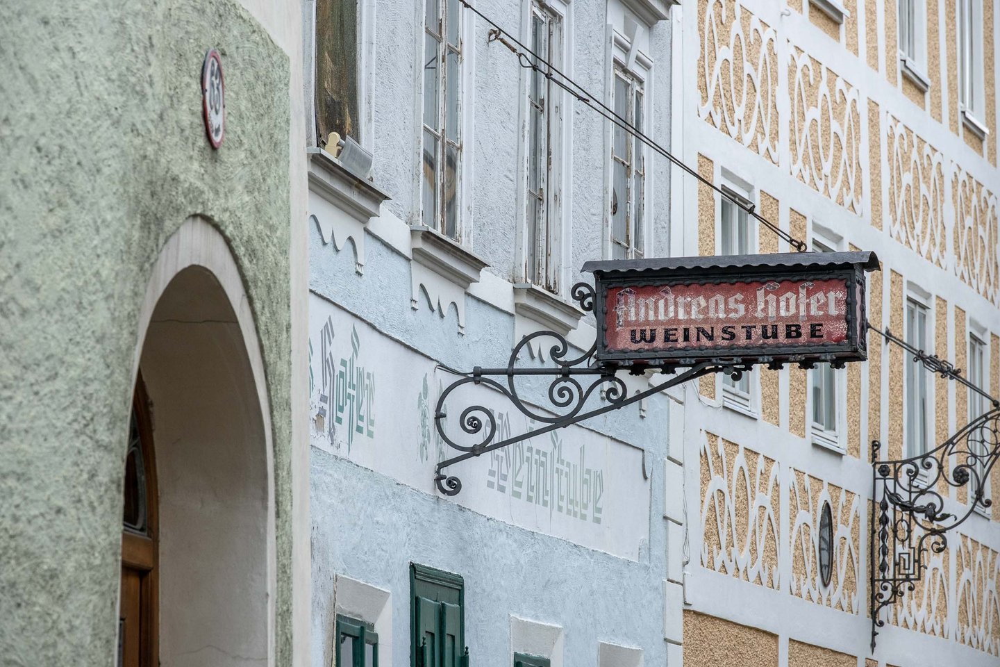 Painted Andreas Hofer Weinstube sign hangs on a sgraffito facade in Steingasse in Salzburg old town.
