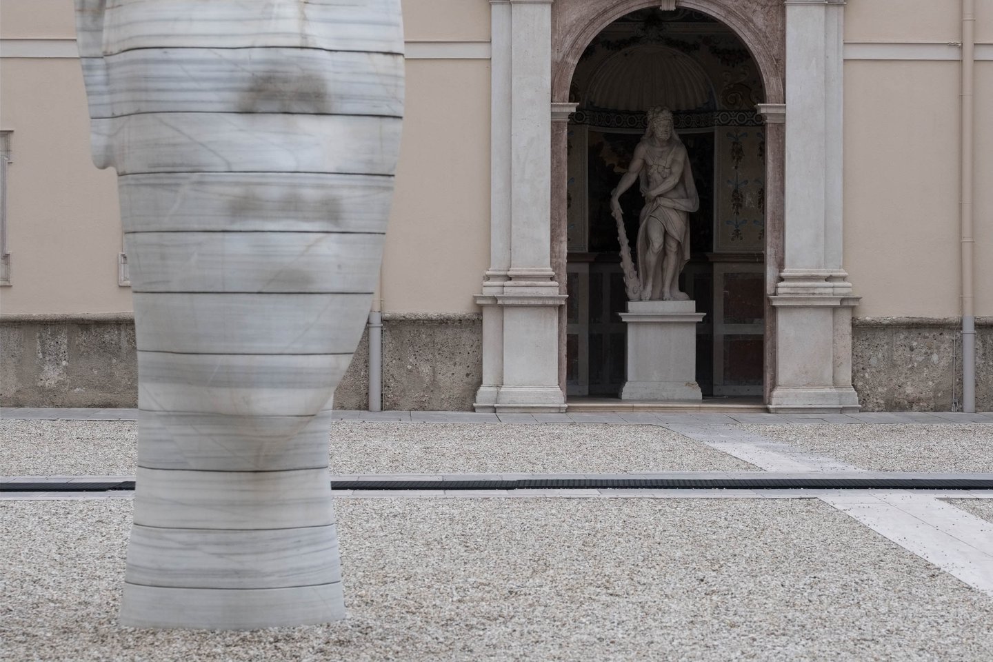 Awilda head sculpture by Jaume Plensa foregrounds a baroque Neptune fountain in Salzburg old town.