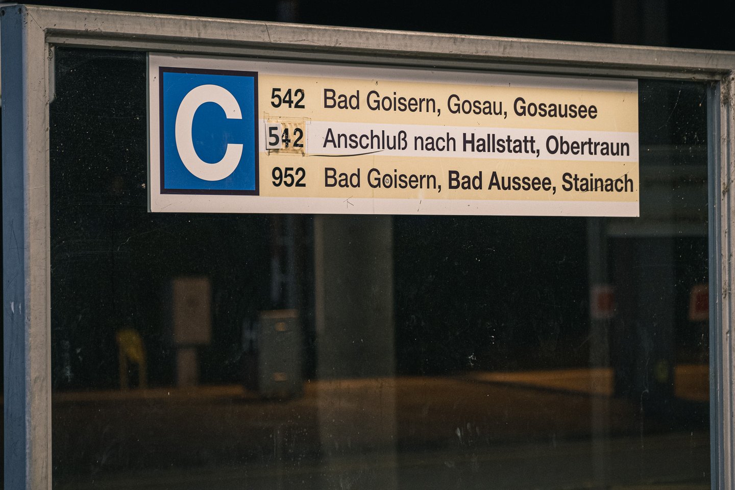A lit departure sign for bay C at Bad Ischl bus terminal lists route 542 to Bad Goisern, Gosau and Gosausee, a connection to Hallstatt and Obertraun, and route 952 to Bad Goisern, Bad Aussee and Stainach.