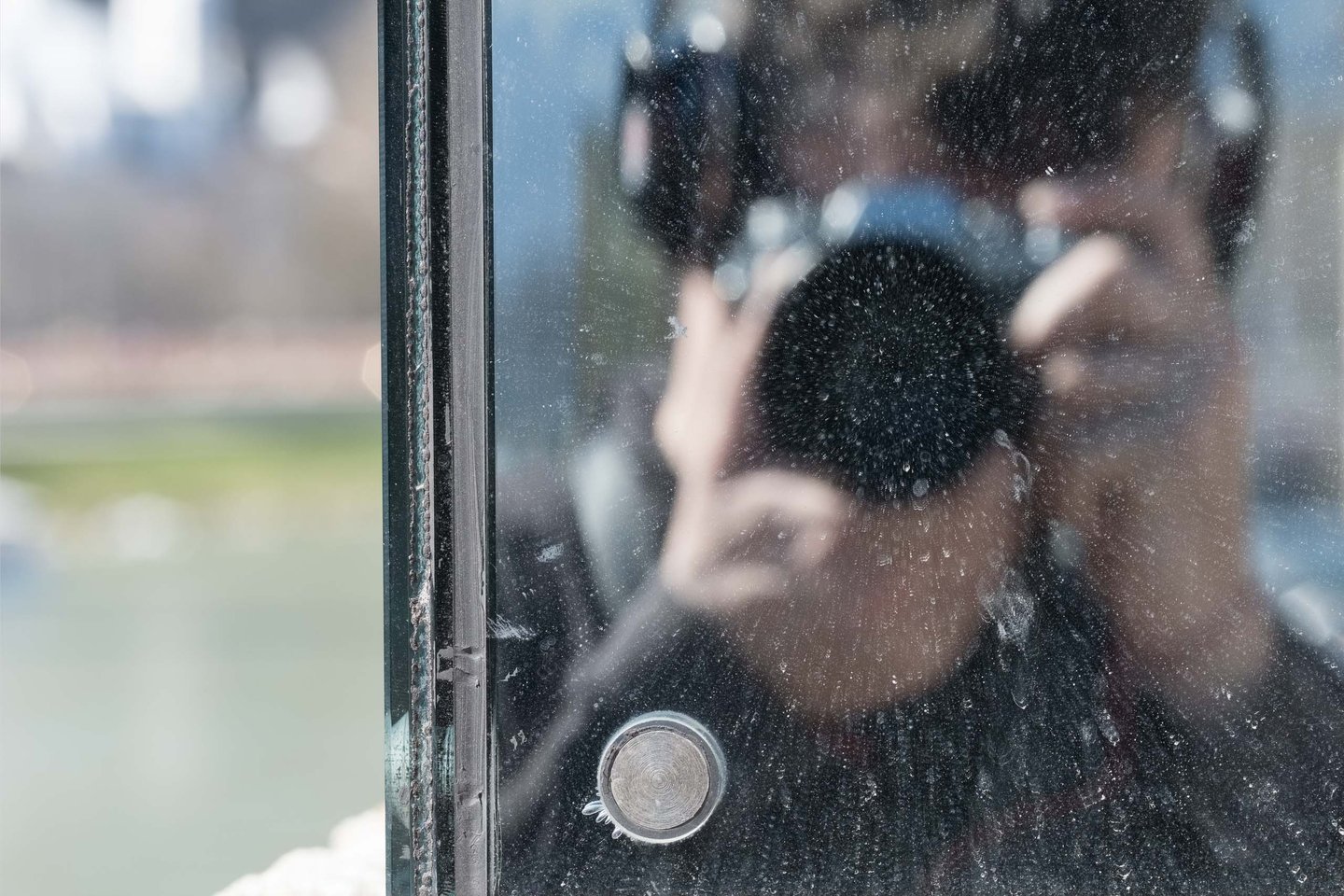 Photographer self-portrait reflected in the Beyond Recall glass artwork on the Staatsbruecke in Salzburg