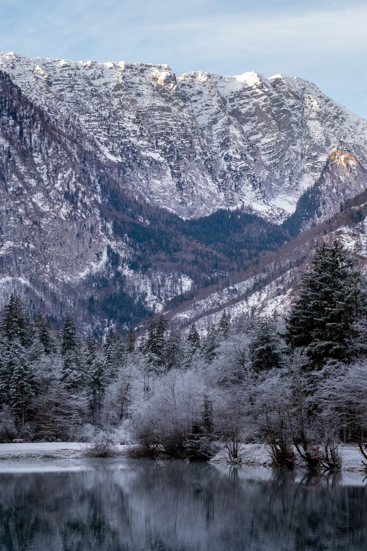 Early sunlight catches the snowy ridge above the Bluntautal while the frosted trees and the Bluntausee below stay in cold shade.