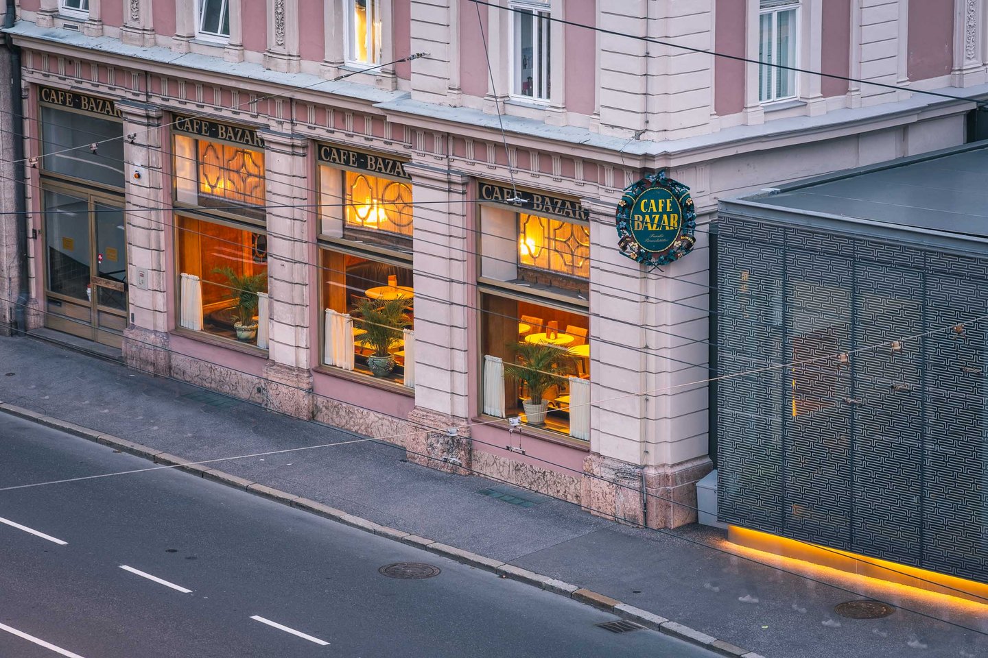 Exterior facade of Cafe Bazar with illuminated windows and signage on Schwarzstrasse in Salzburg.